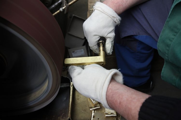 Herstellung eines Walter Gropius Türdrückers Tecnolumen: Schleifen einer Messing-Türklinke für eine matte Nickel-Oberfläche.
