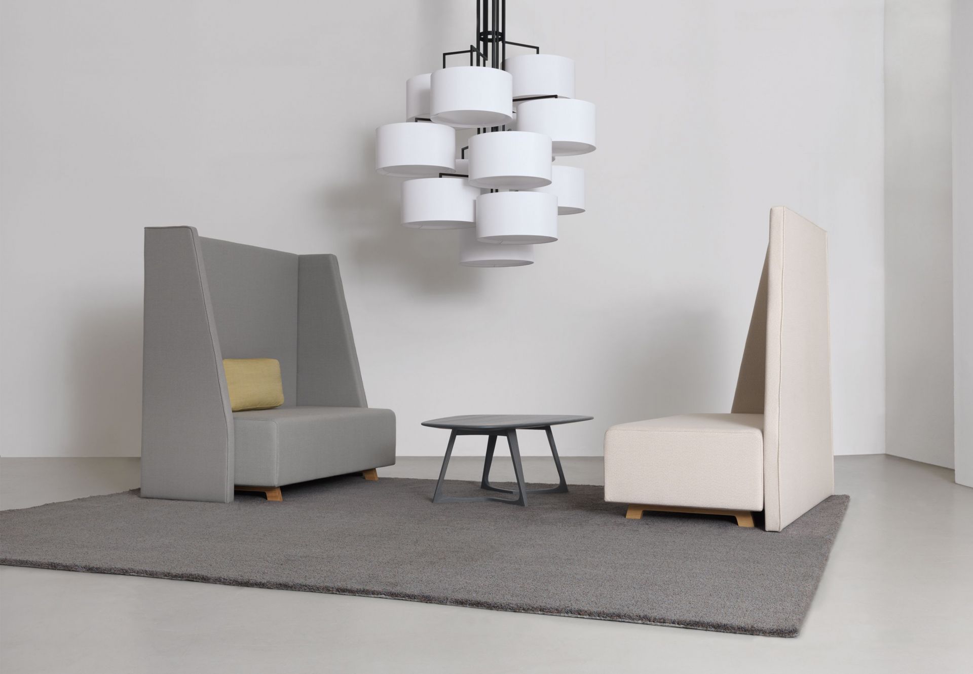 NOON 12 Deckenleuchte in Warmgrau über Lounge-Bereich mit Sesseln und Teppich. Moderne Innenraumbeleuchtung.