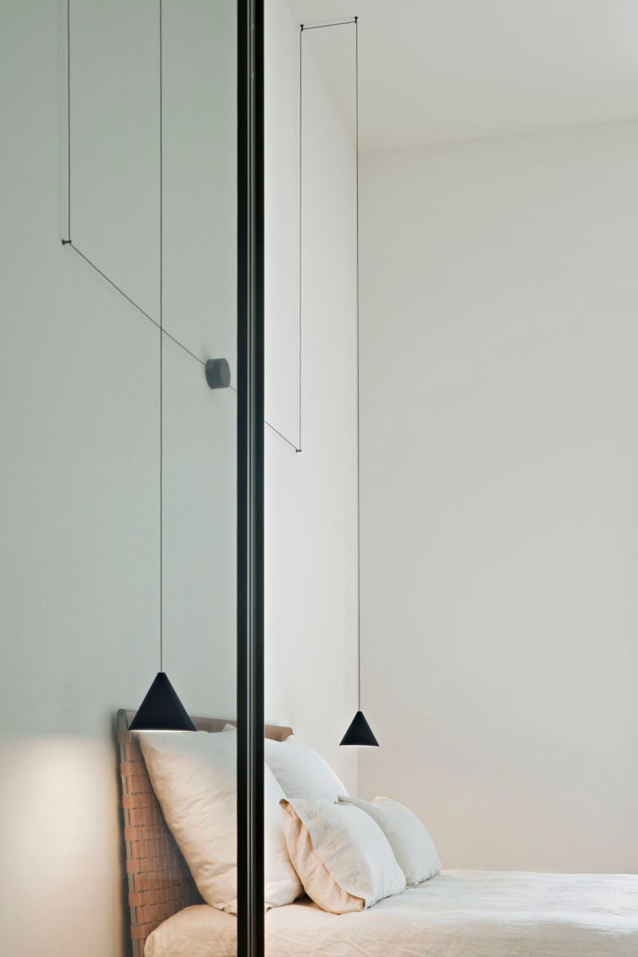 Flos String Light Pendelleuchte mit Wandrosette über Bett, modernes Design, minimalistische Hängelampe.