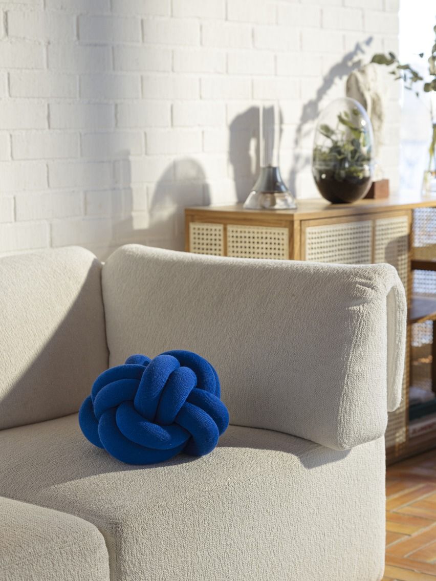 Blaues Knot Kissen von Design House Stockholm auf einem beigen Sofa, dekoratives Wohnaccessoire.
