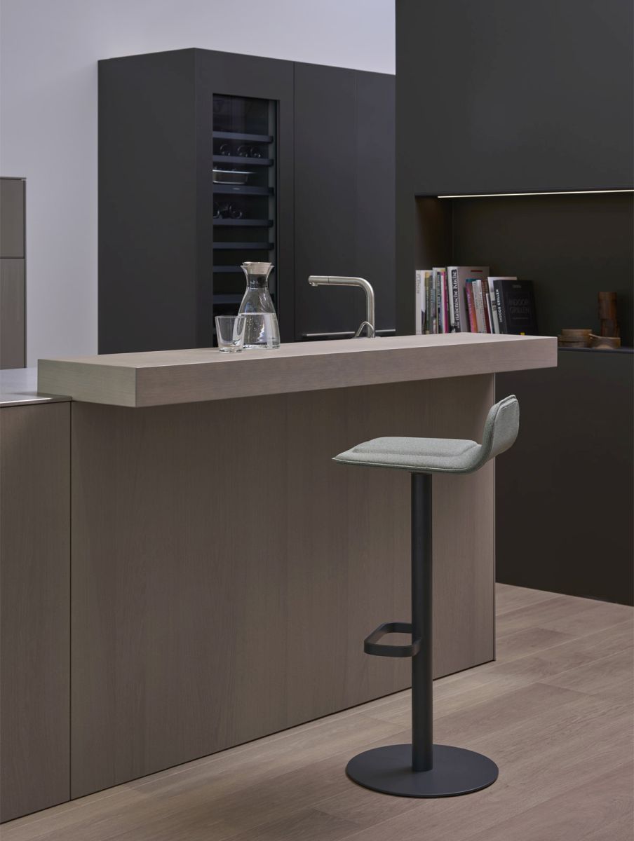 Anthrazitfarbener Dave Barhocker von Moree mit weinrotem Sitzpolster vor einer modernen Kücheninsel.