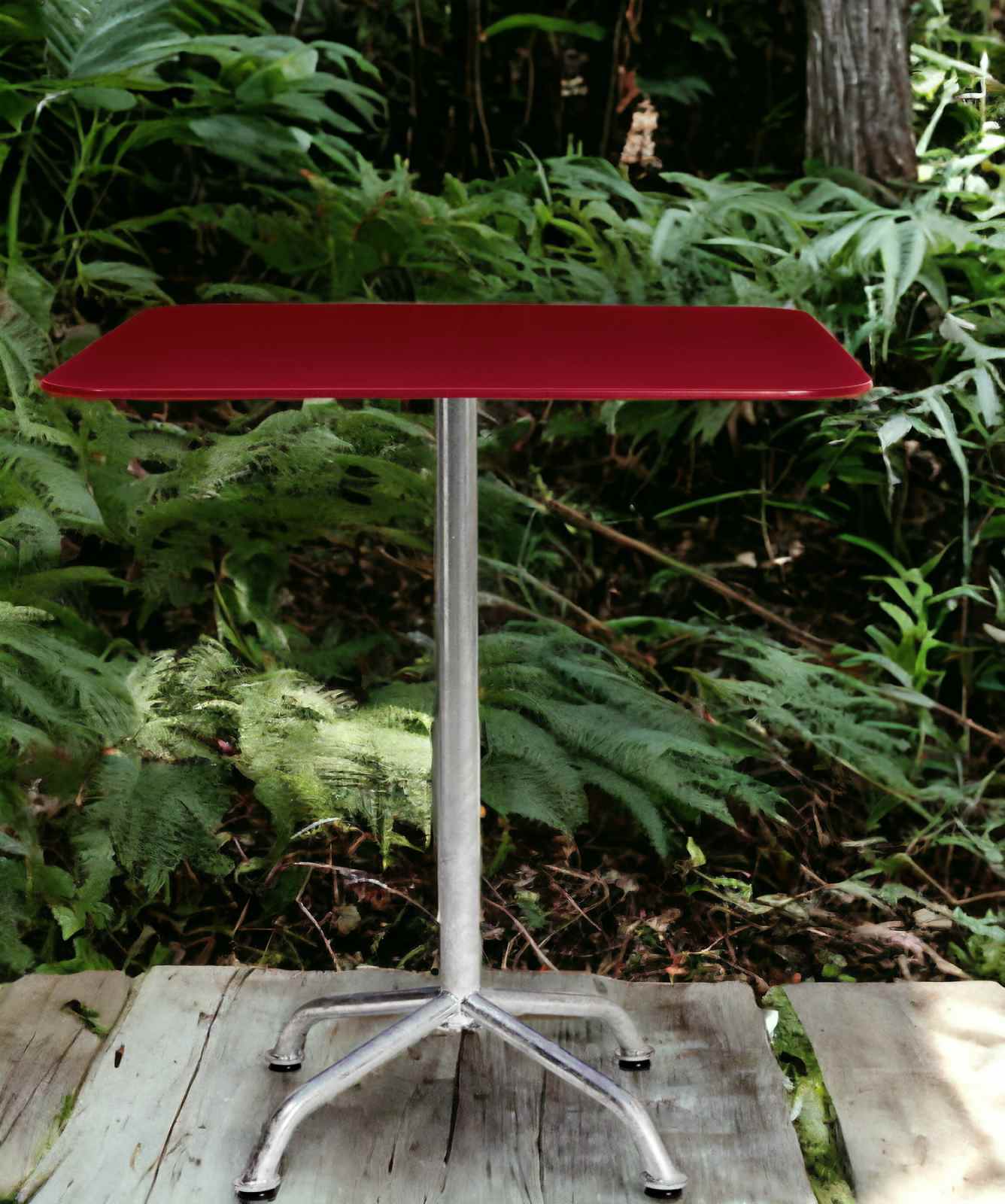 Roter Haefeli Gartentisch mit Stahlgestell im Freien vor üppigem Grün. Outdoor Tisch.