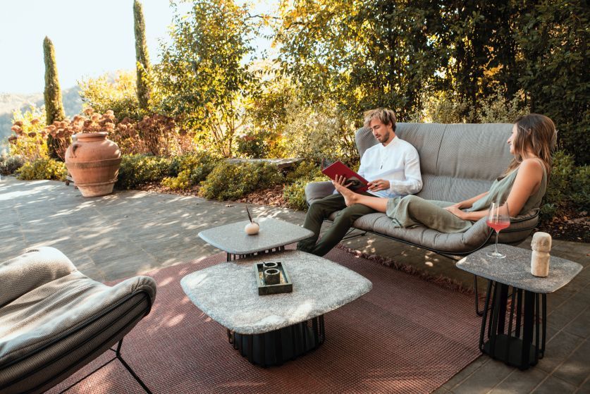 BC 09 Basket Beistelltisch von Janua, Travatin Sriato, auf einer Terrasse mit Menschen und Garten.