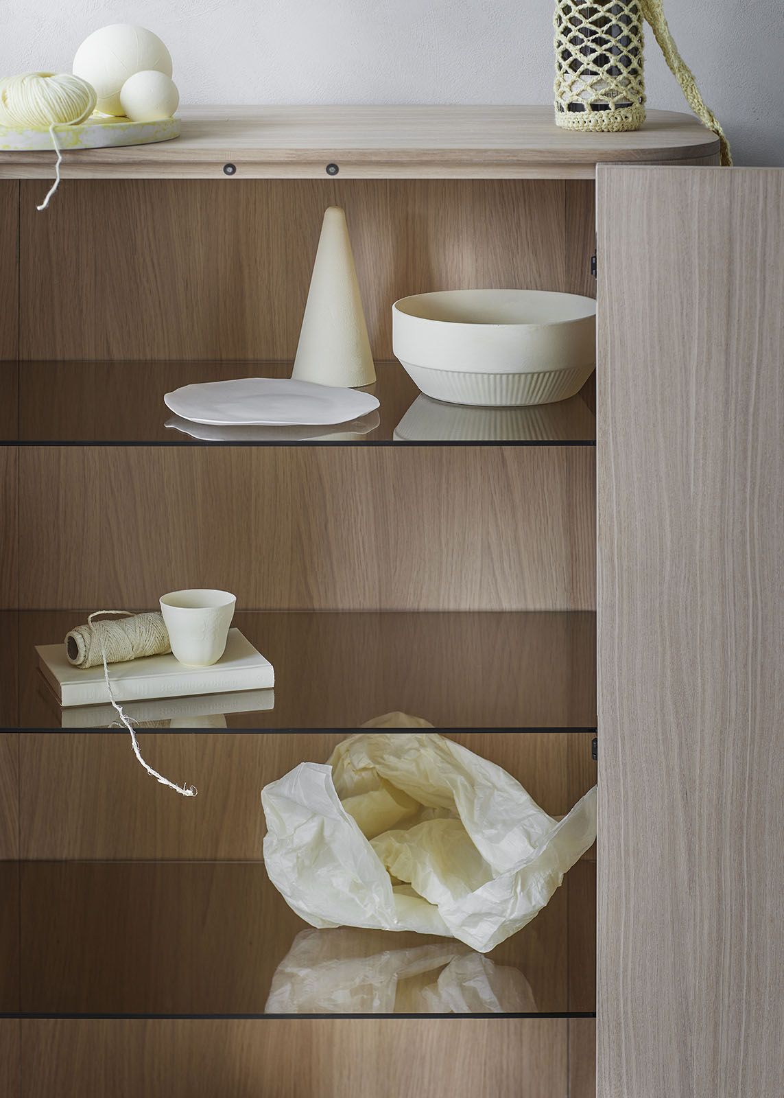 Detailaufnahme: Loud Schrank aus geräucherter Eiche mit Glasböden und dekorativen Objekten.