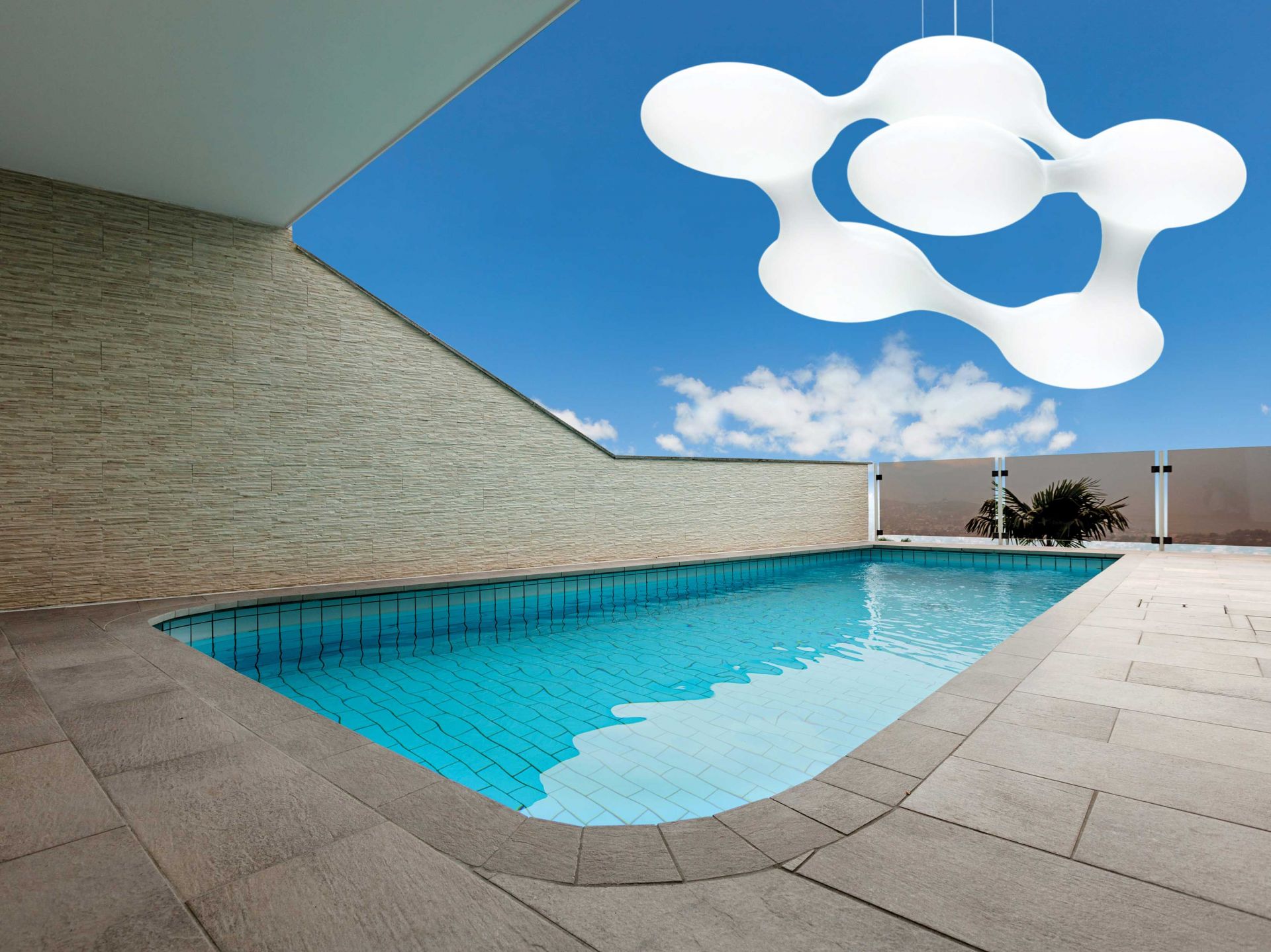 Weiße Cosmo Pendelleuchte Outdoor über Pool mit blauem Himmel im Hintergrund. Moderne Außenleuchte.