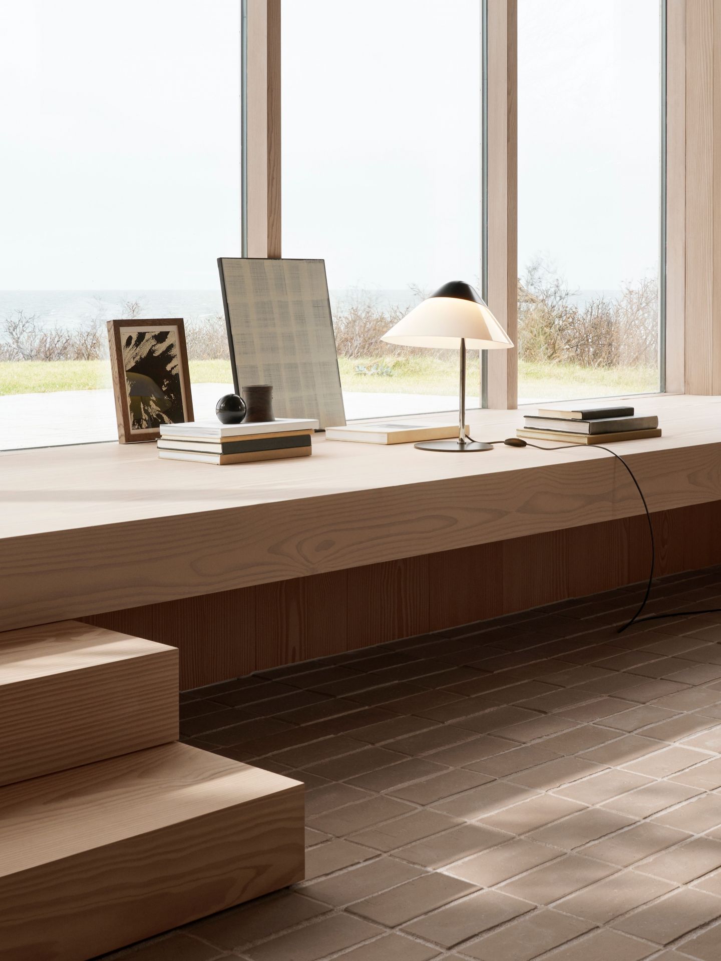 Helle HJW02 Tischleuchte von Carl Hansen & Søn auf Fensterbank mit Büchern.