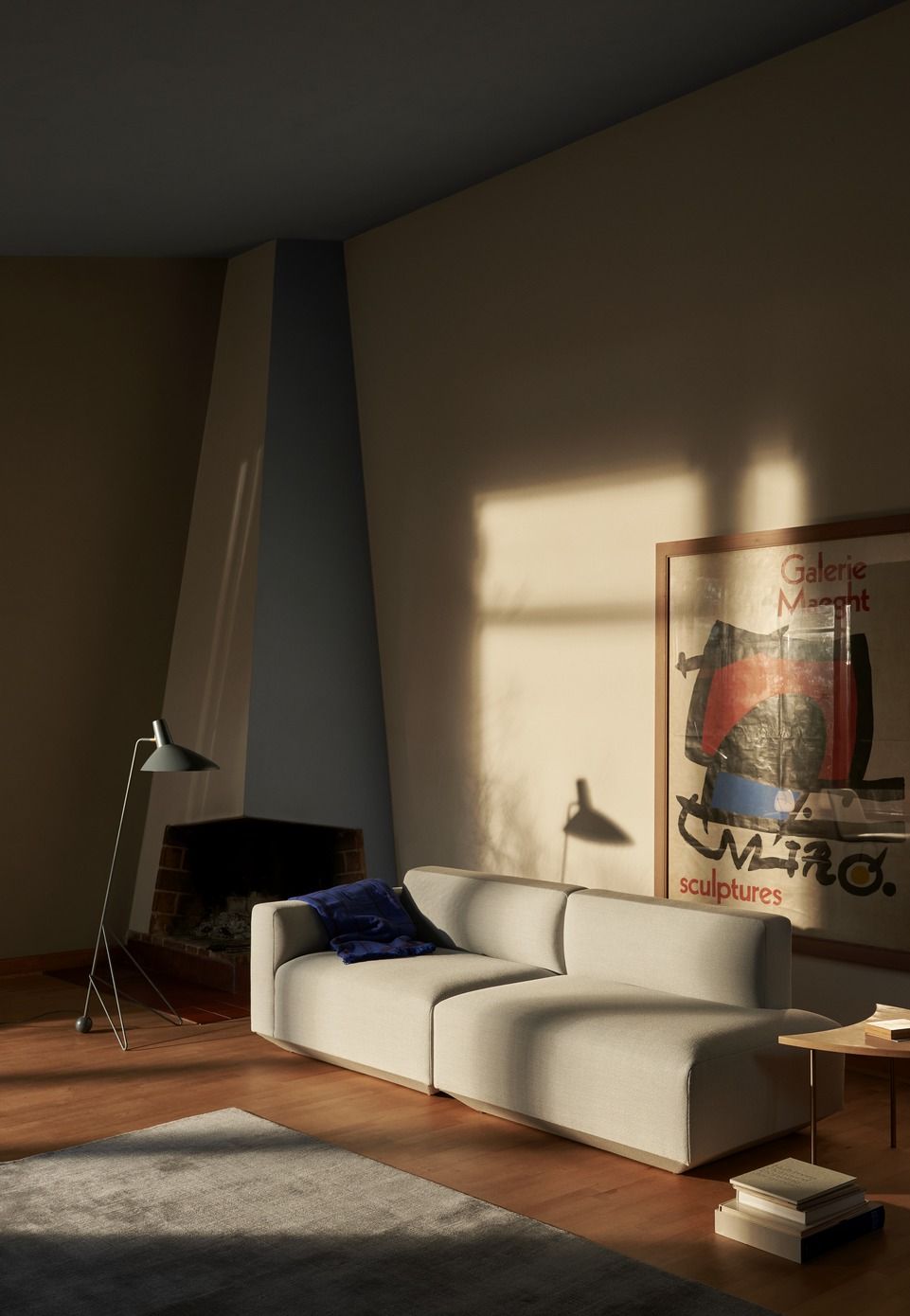 Beige Develius Sofa von AndTradition im Wohnzimmer mit Kamin und Kunstposter. Modulares Sofa für modernes Wohnen.