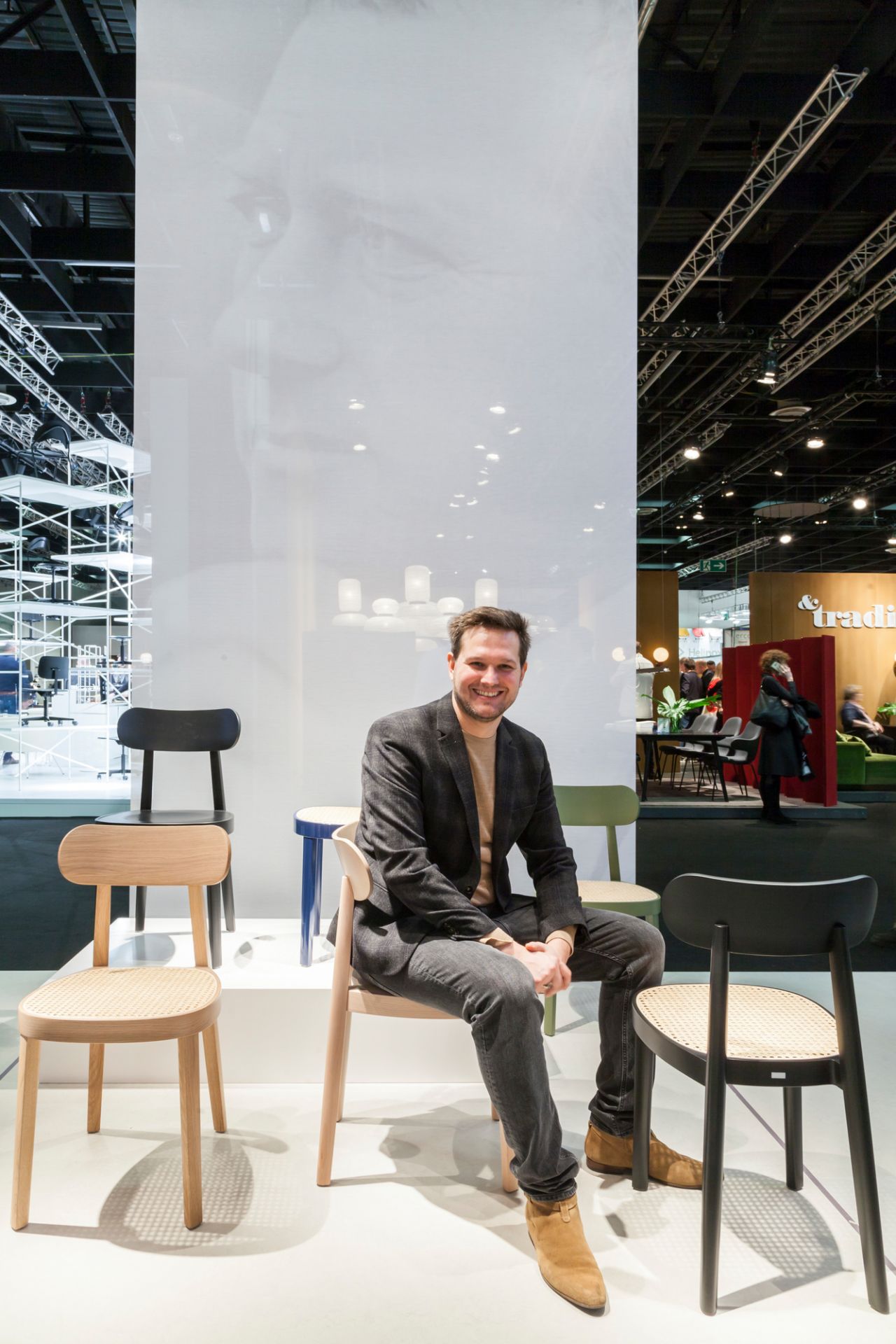 Mann sitzt auf einem hellen Holzstuhl, Thonet 118 M ähnlich, mit Wiener Geflecht.