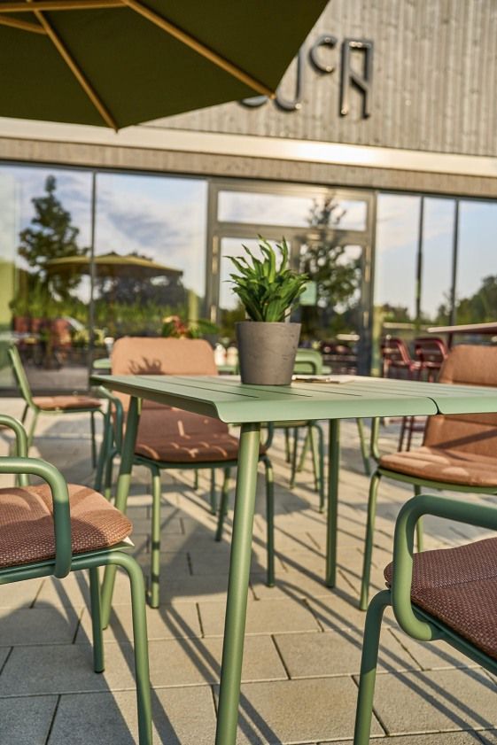 Weishäupl Vapio Sessel und Tisch für den Außenbereich in Grün mit braunen Sitzflächen.