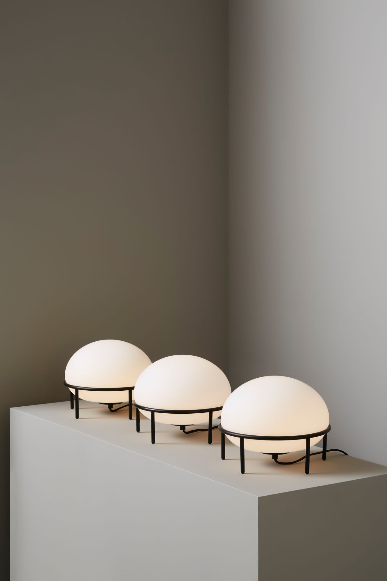 Drei Woud Pump Table Lamp Tischleuchten mit runden, weißen Lampenschirmen und schwarzem Gestell.