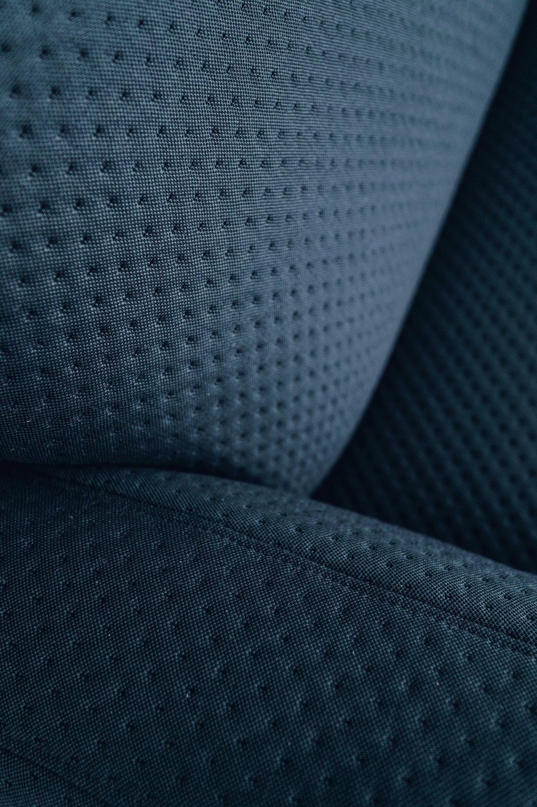 Detailaufnahme des blauen Stoffbezugs vom Auguste Sessel Hartô mit feiner Punktstruktur. Komfortabler Design Sessel.