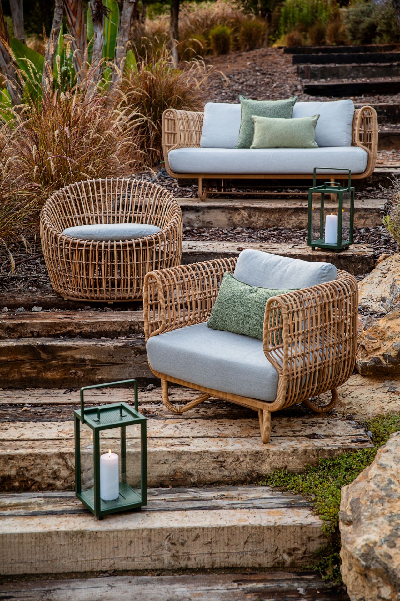 Nest Outdoor Sofa und Sessel aus Rattan mit weißen Kissen für Garten und Terrasse.