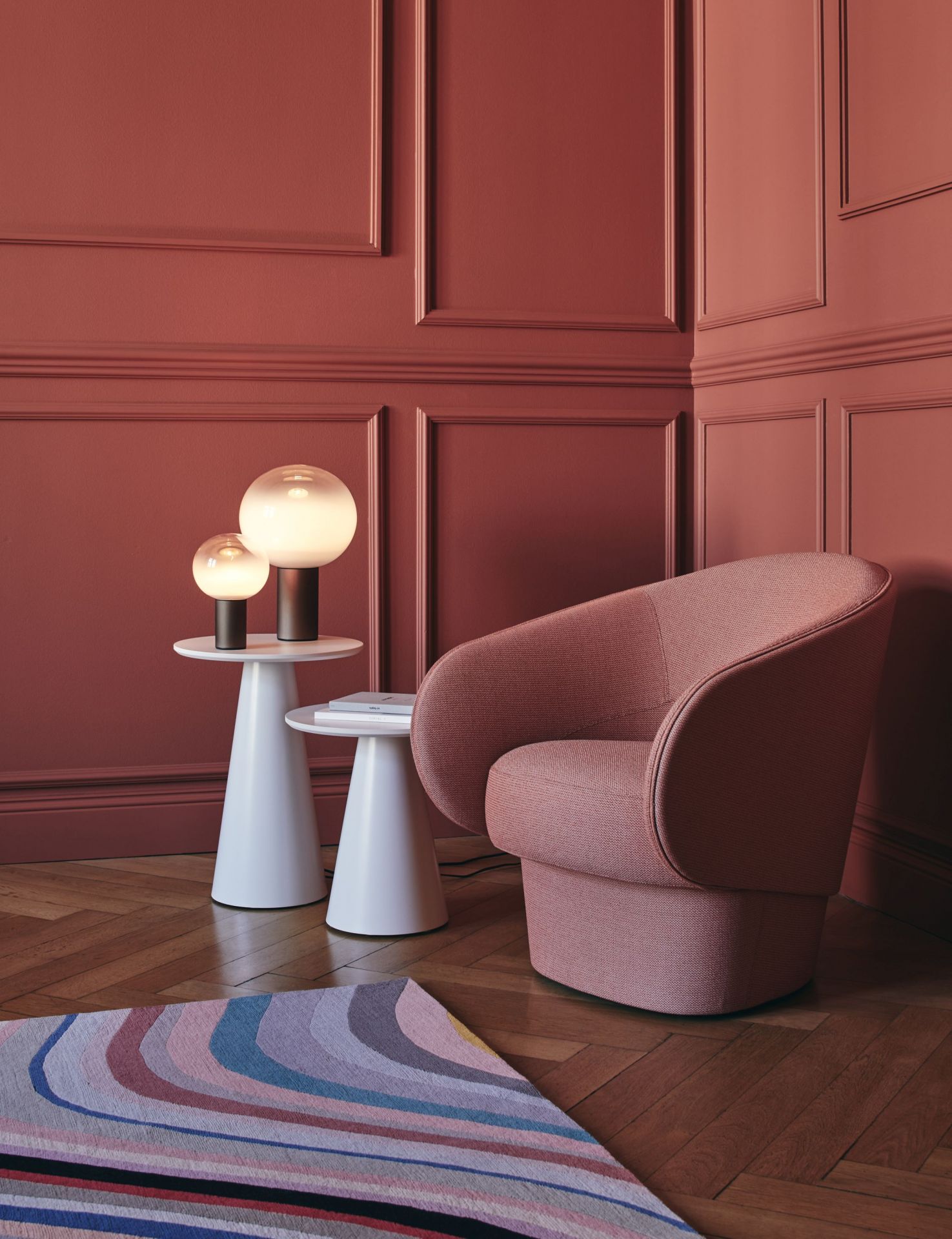 Laguna Tischleuchte von Artemide in Bronze auf weißem Beistelltisch, neben Sessel.