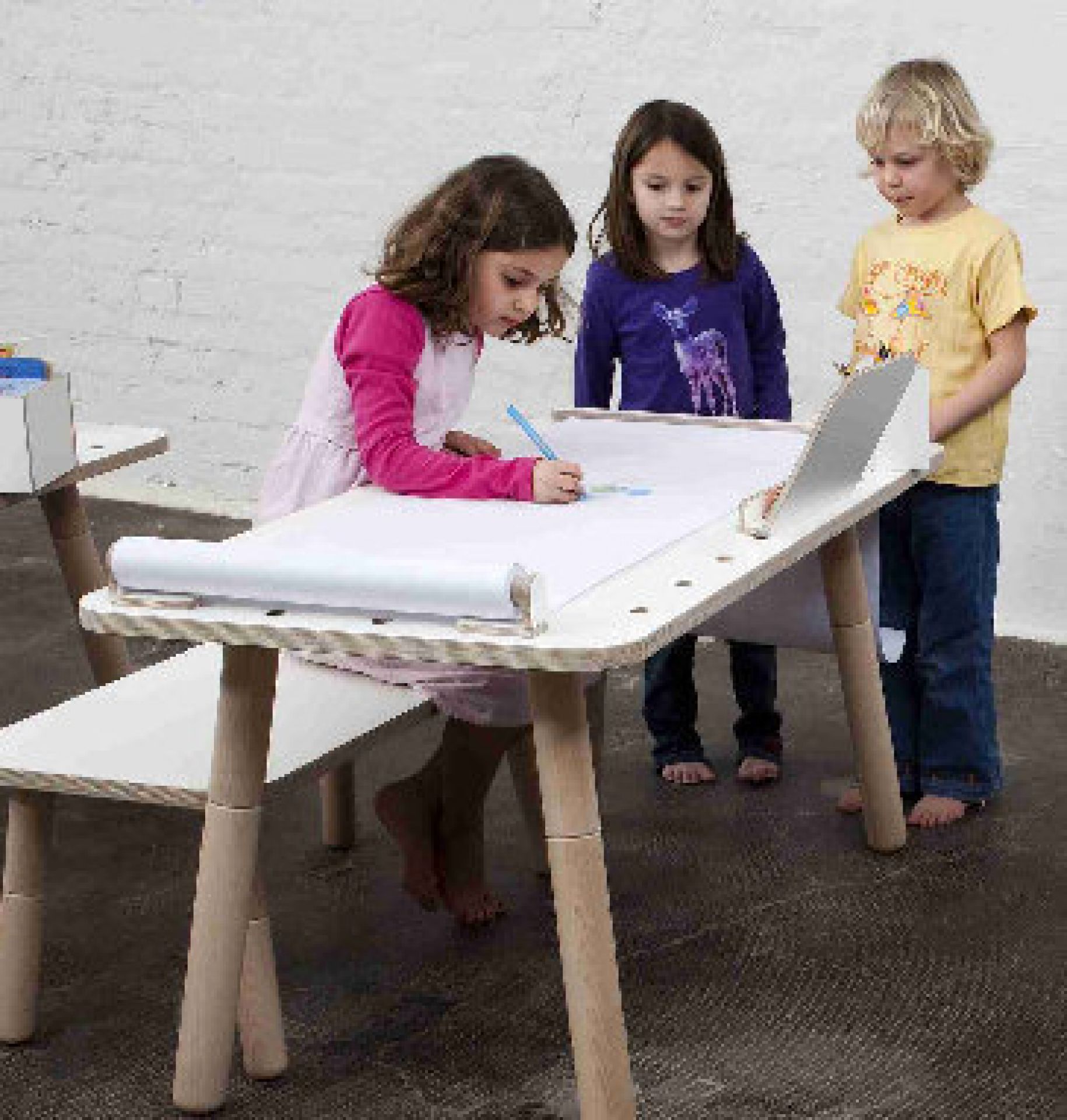 Kinder zeichnen am Kindertisch mit Papierrolle und Abreißschiene. Growing Table Zubehör für kreatives Spielen.