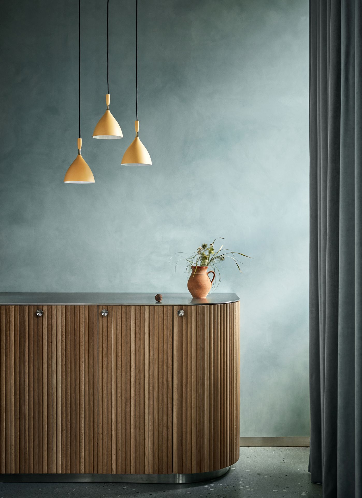 Drei gelbe Dokka Pendelleuchten von Northern über einem Holzschrank mit Vase.