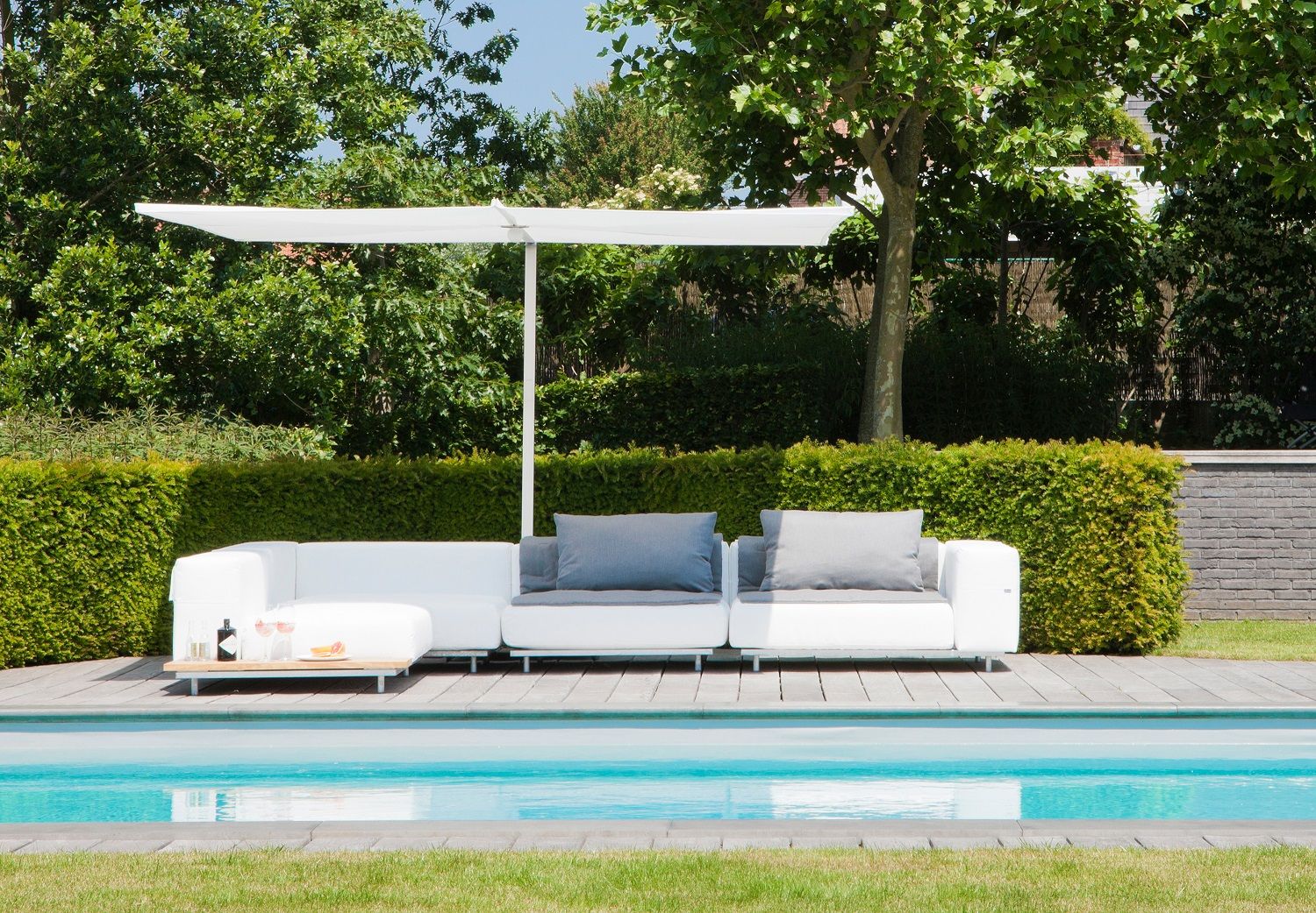 Walrus Outdoor Sofa Mittelmodul von Extremis in Weiß mit grauen Kissen am Pool.