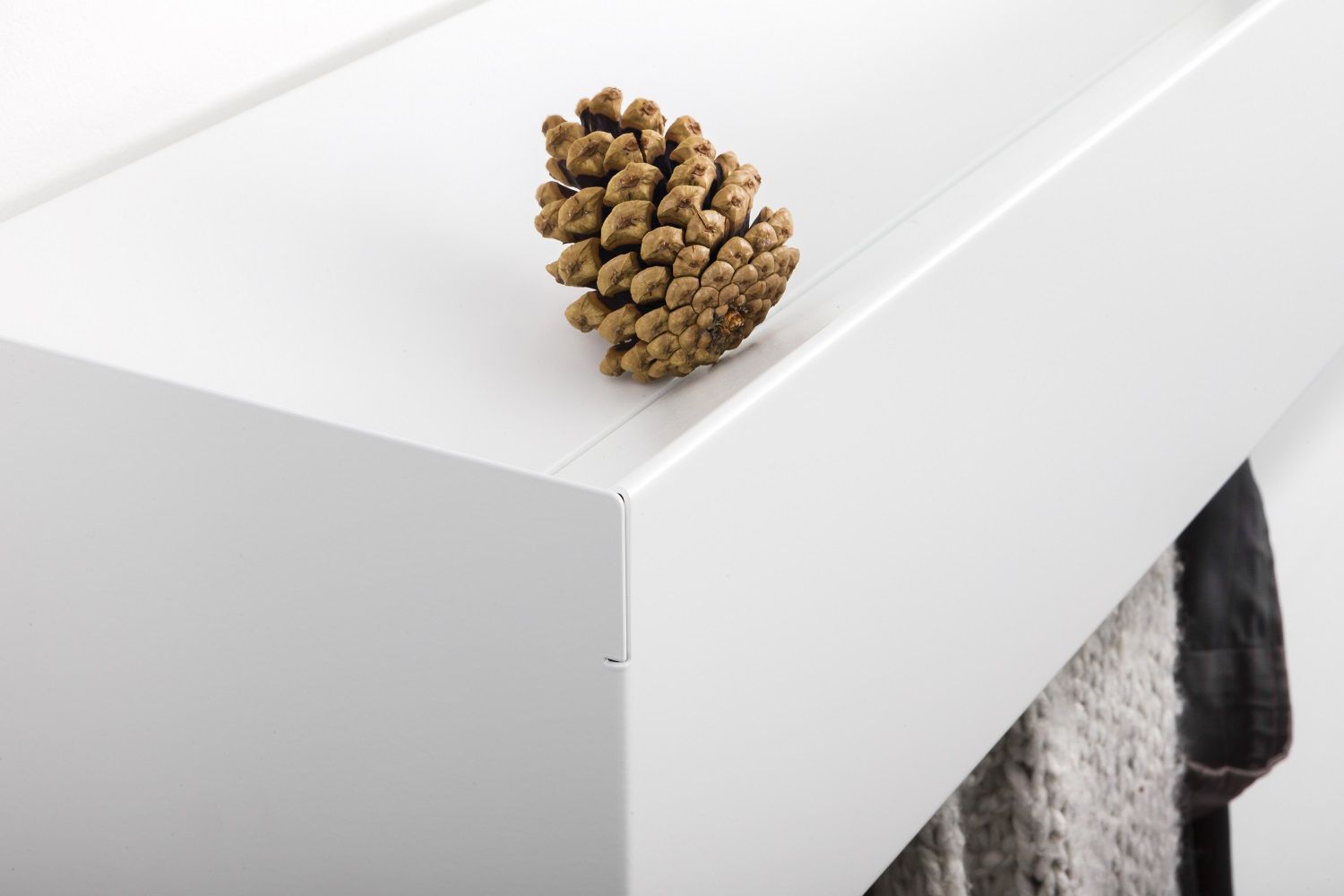 Weiße Wandgarderobe CR Linea1 von Müller Möbelwerkstätten mit Zapfen als Deko und Jackenaufhängung.