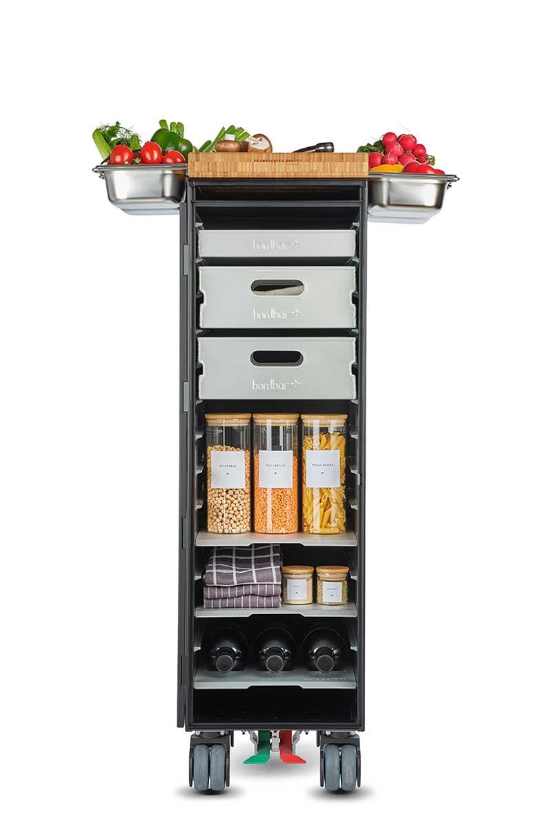 Bordbar Servierwagen mit Zubehör: Schneidebrett, Behälter mit Gemüse, Vorratsbehälter und Weinflaschen.