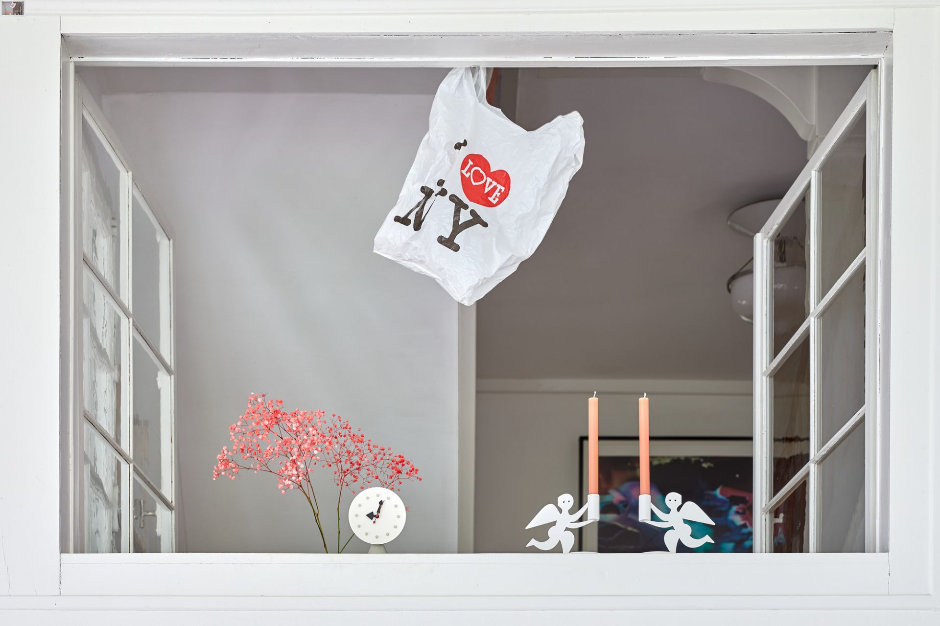 Weiße Vitra Tischuhr mit Kegelbasis, kombiniert mit Dekorationen in einem Fensterrahmen.