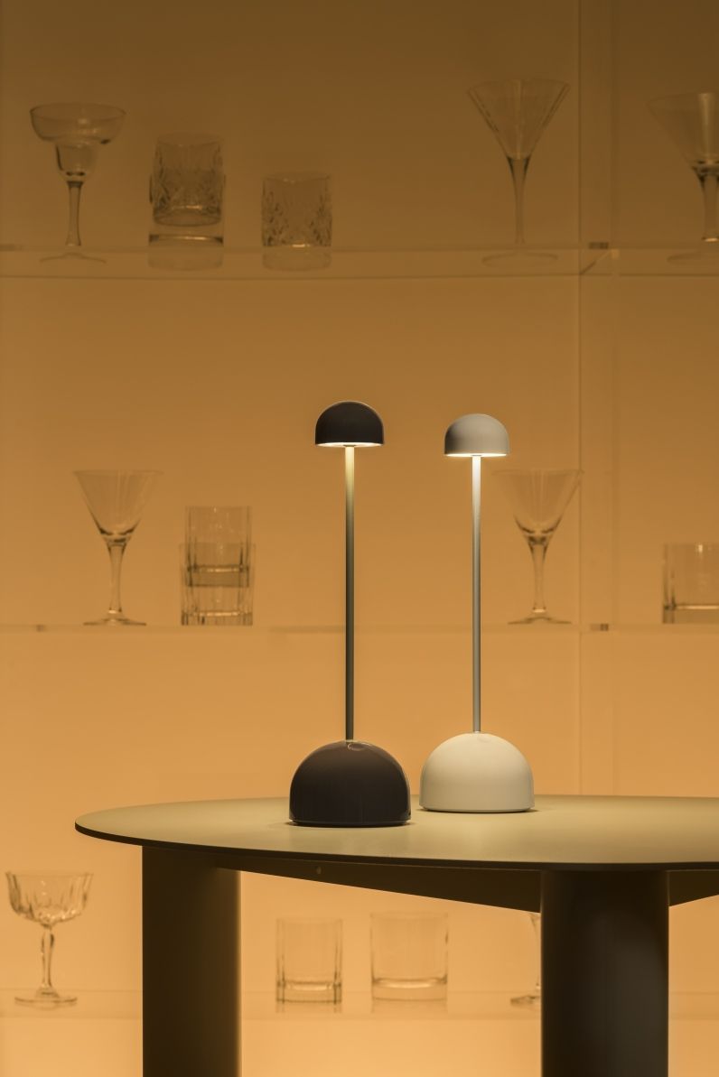 Sips Akkuleuchte von Marset in Grün und Gold auf einem Tisch.