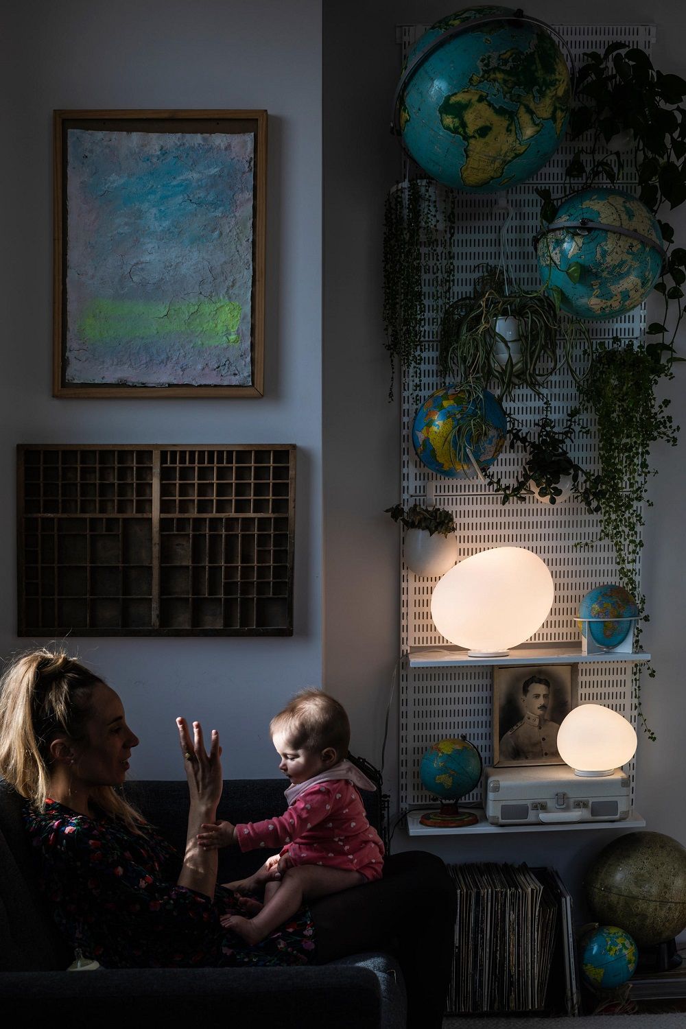 Frau und Baby sitzen neben zwei leuchtenden Gregg Tischleuchten von Foscarini.