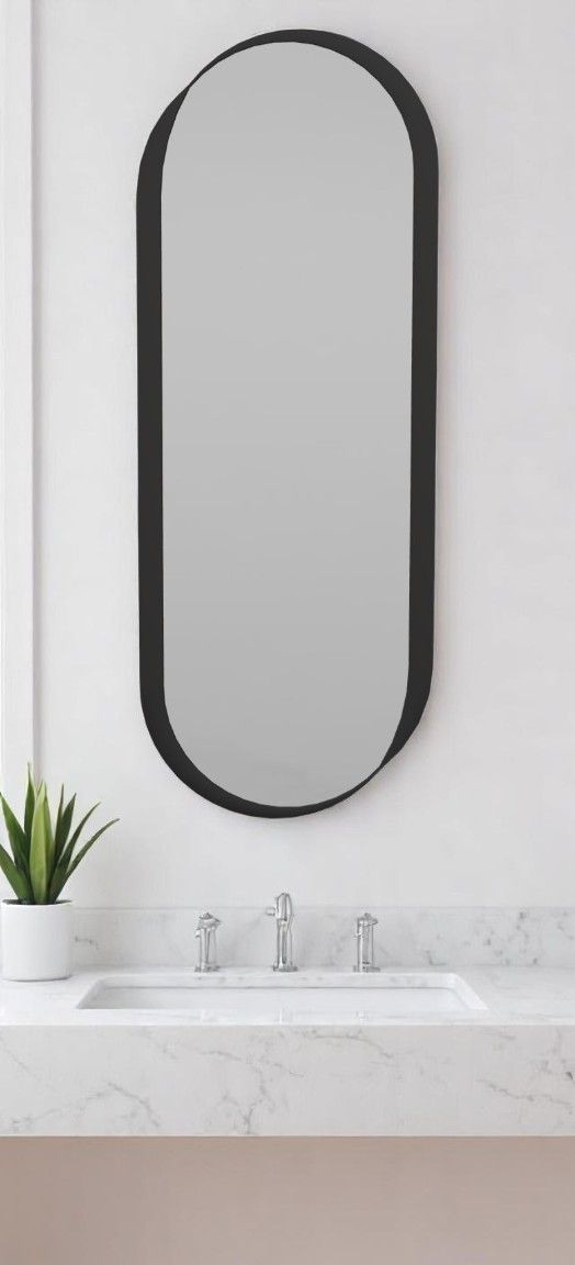 Kimo Wandspiegel von Schönbuch, oval mit schwarzem Rahmen, über einem Waschbecken im Badezimmer.