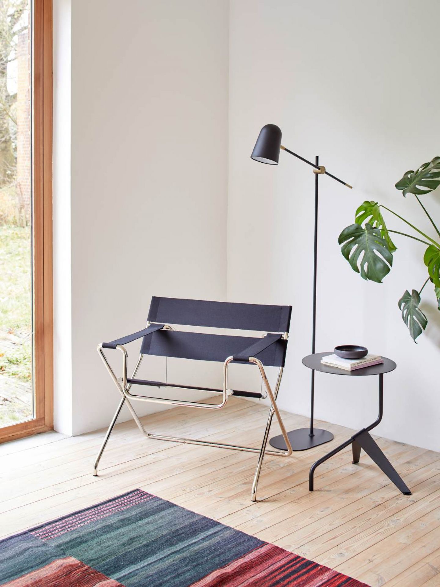 Weißer Tecta K5B Beistelltisch/Couchtisch neben einem Sessel und einer Stehlampe in einem hellen Raum.