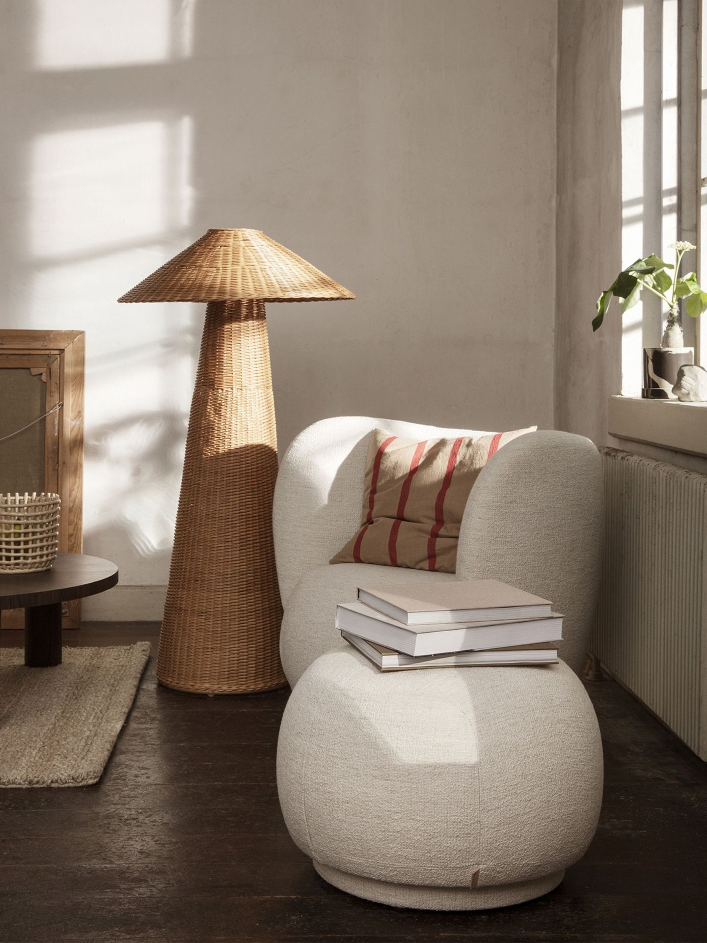 Beiger Rico Pouf von Ferm Living mit Büchern und Kissen in einem hellen Wohnzimmer.