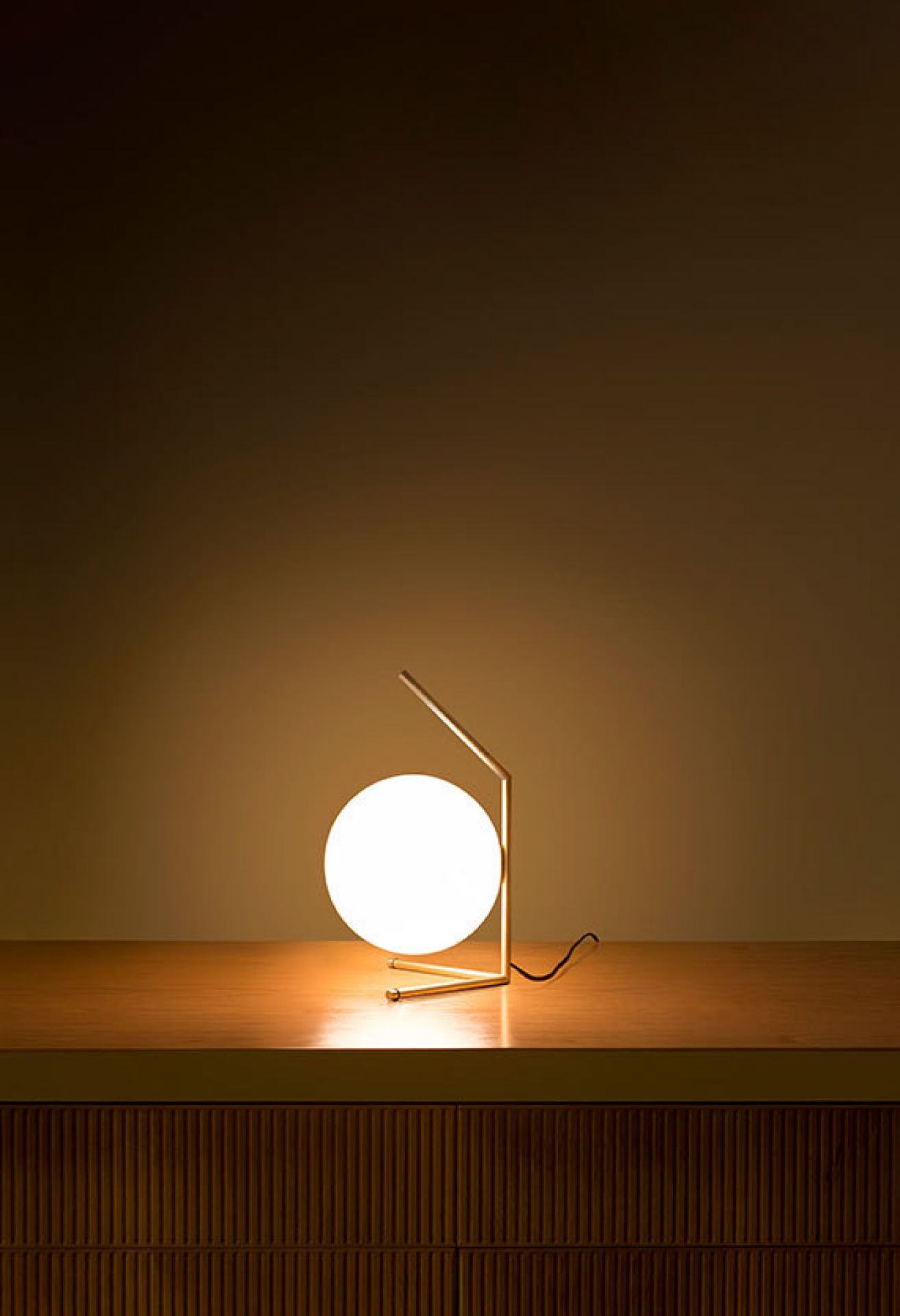 IC Lights T1 Low Tischleuchte von Flos: Moderne Tischlampe mit goldenem Gestell und leuchtender Kugel.