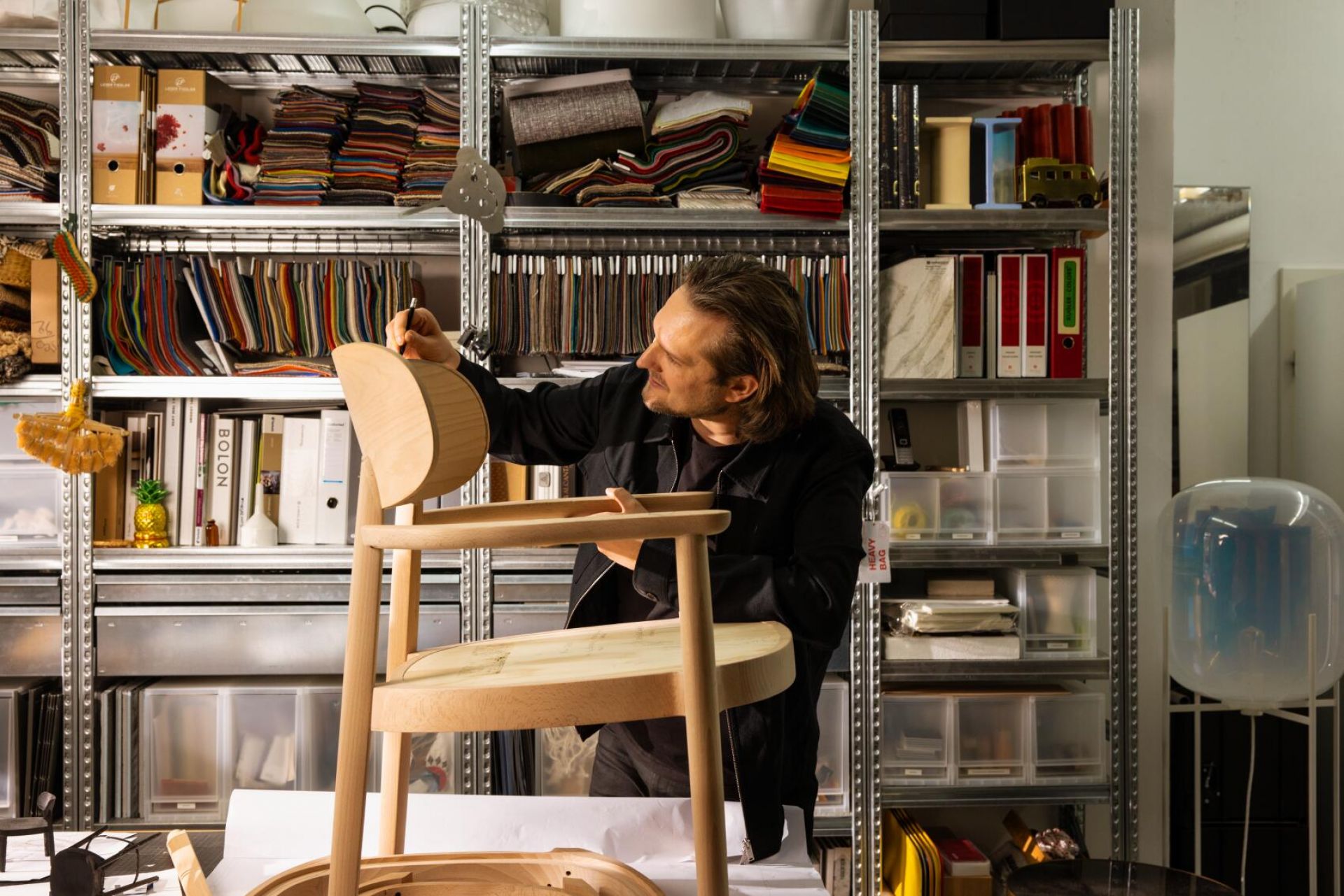 Mann arbeitet an einem hellen Holzsessel mit Armlehnen, möglicherweise ein Thonet Stuhl.