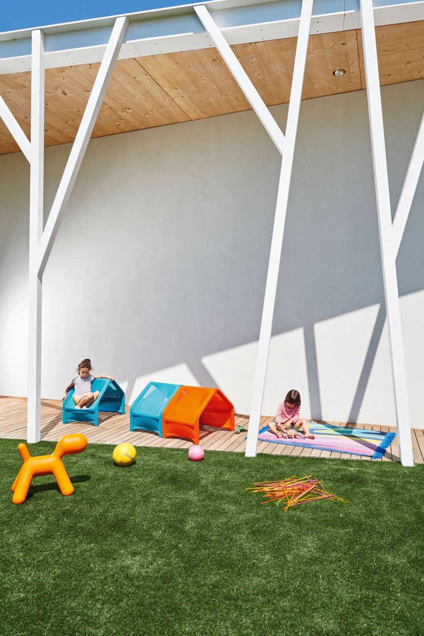 Zwei Kinder spielen mit dem Magis Puppy Spielhund und bunten Spielhäusern im Garten.