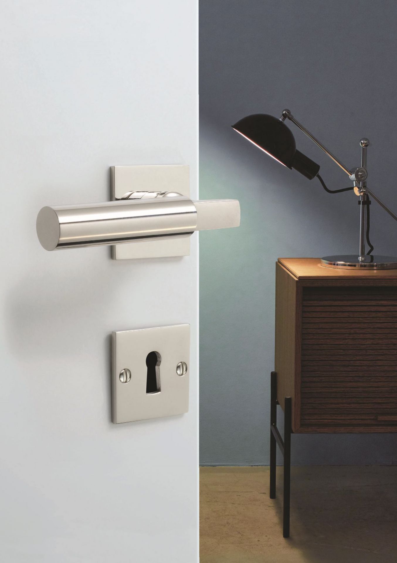 Walter Gropius Türdrücker Tecnolumen aus Edelstahl, Detailaufnahme mit Schlüsselloch und Nachttischlampe im Hintergrund.
