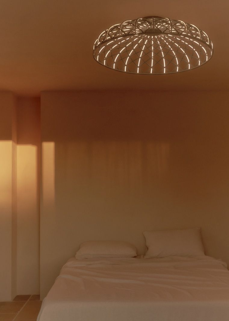 Skynest Deckenleuchte von Flos über einem Bett. Moderne Hängelampe mit filigranem Design.