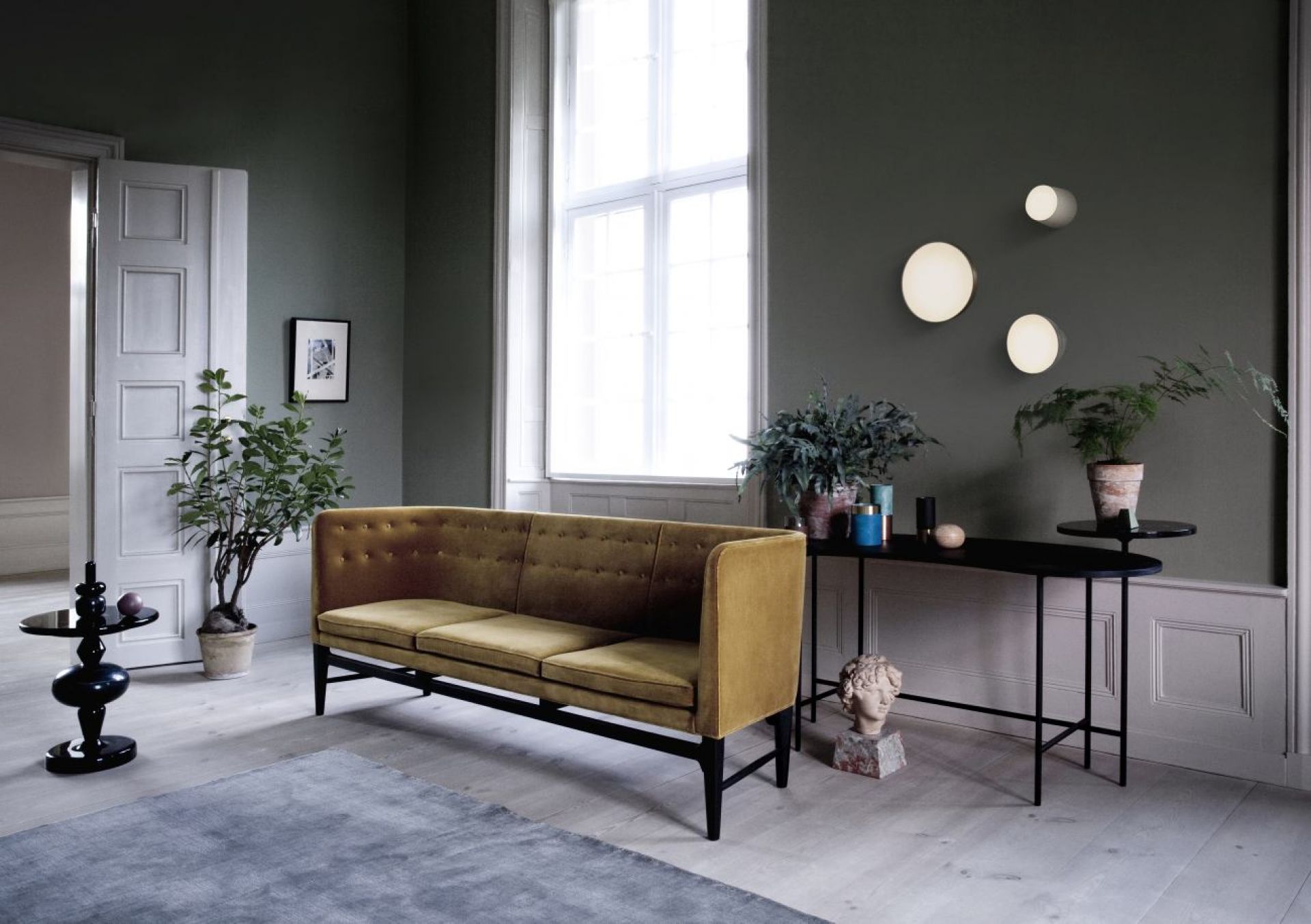 Wohnzimmer mit AndTradition Sofa, schwarzem Konsolentisch und runden Wandleuchten. Interior Design Möbel.