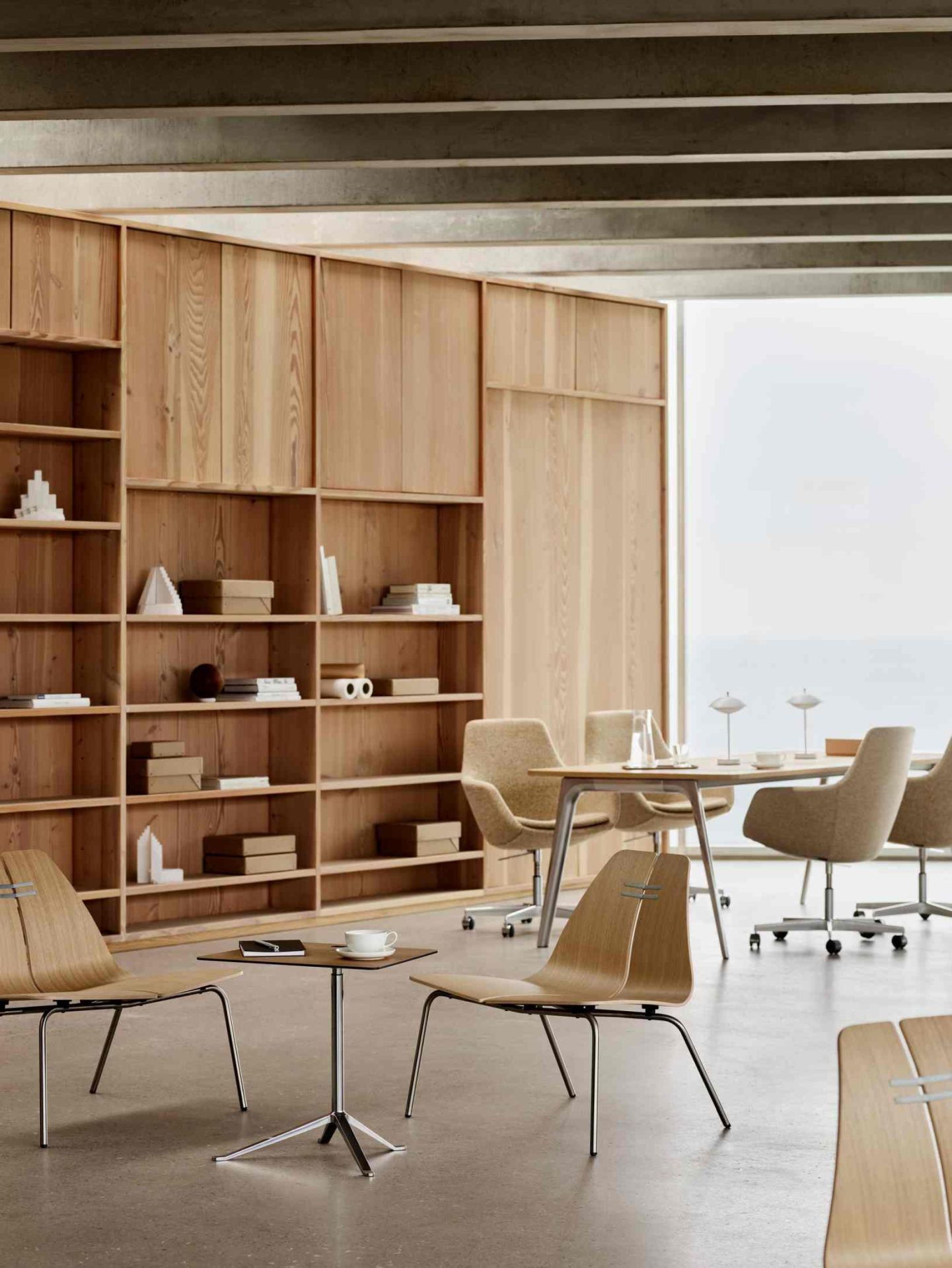 PK23 Sessel von Fritz Hansen in hellem Raum mit Holzwand und Besprechungstisch.