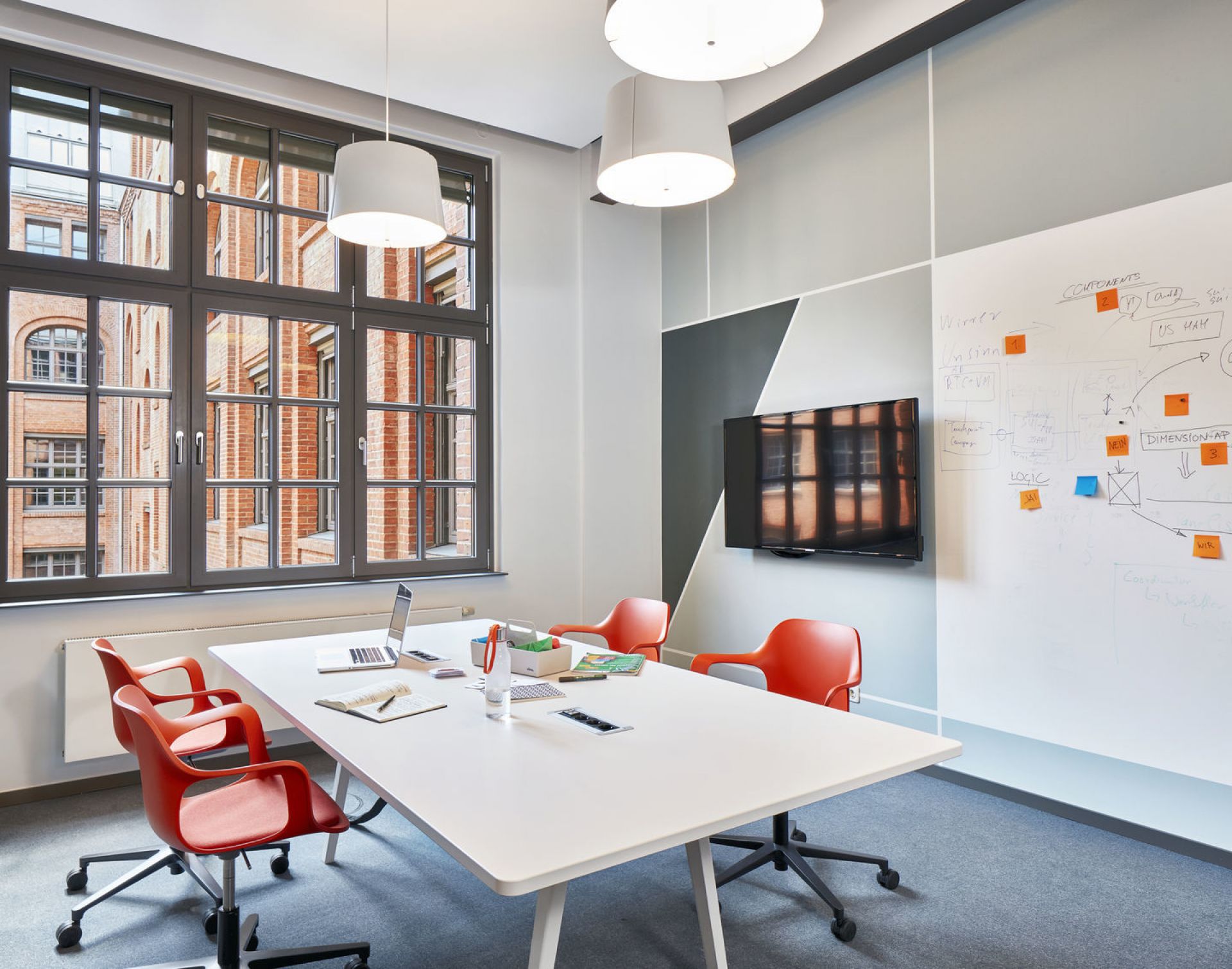 Besprechungsraum mit weißem Tisch und orangefarbenen Hal Drehstühlen von Vitra. Büro- und Konferenzmöbel.