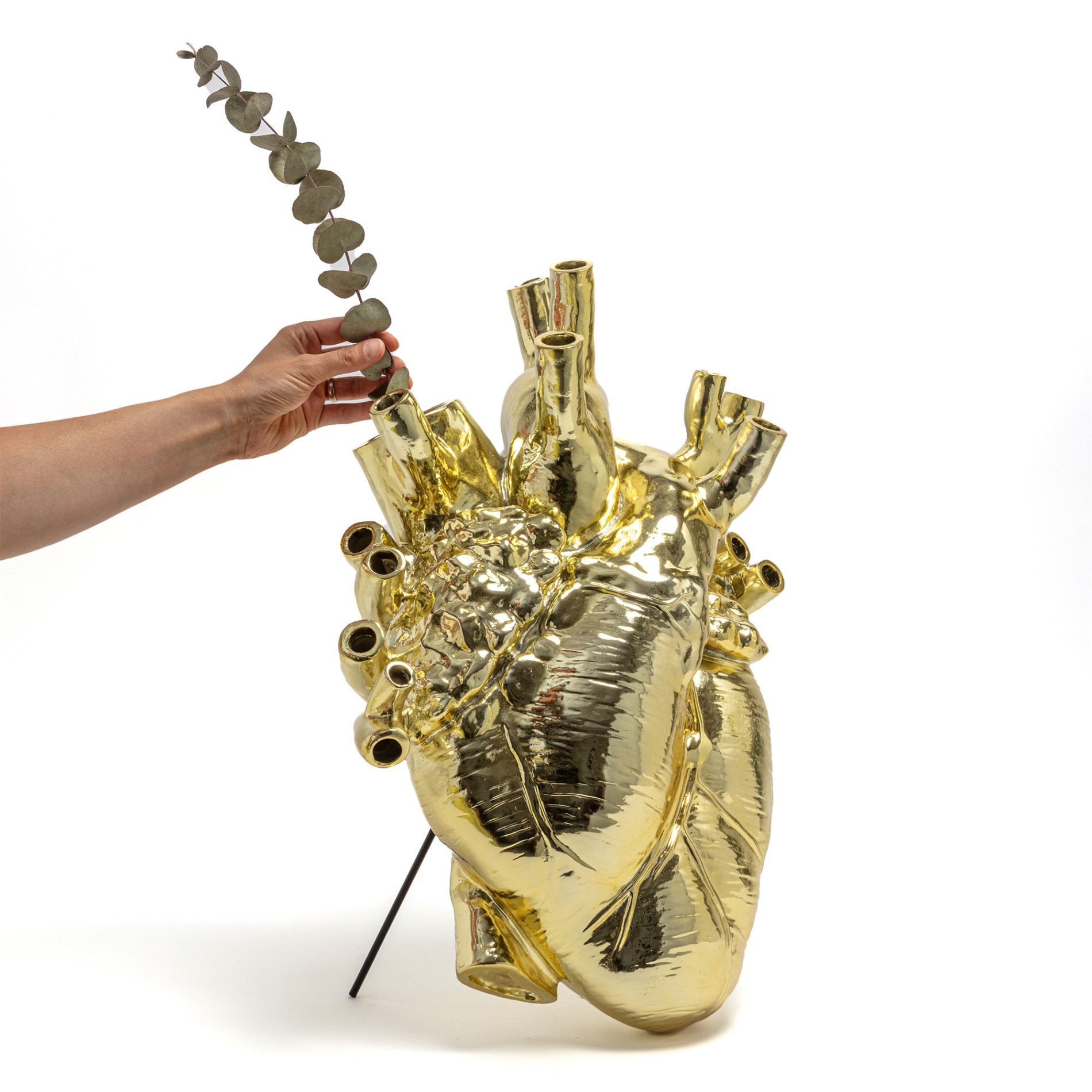 Goldene Love in Bloom Vase in Herzform von Seletti mit Hand und Eukalyptus.