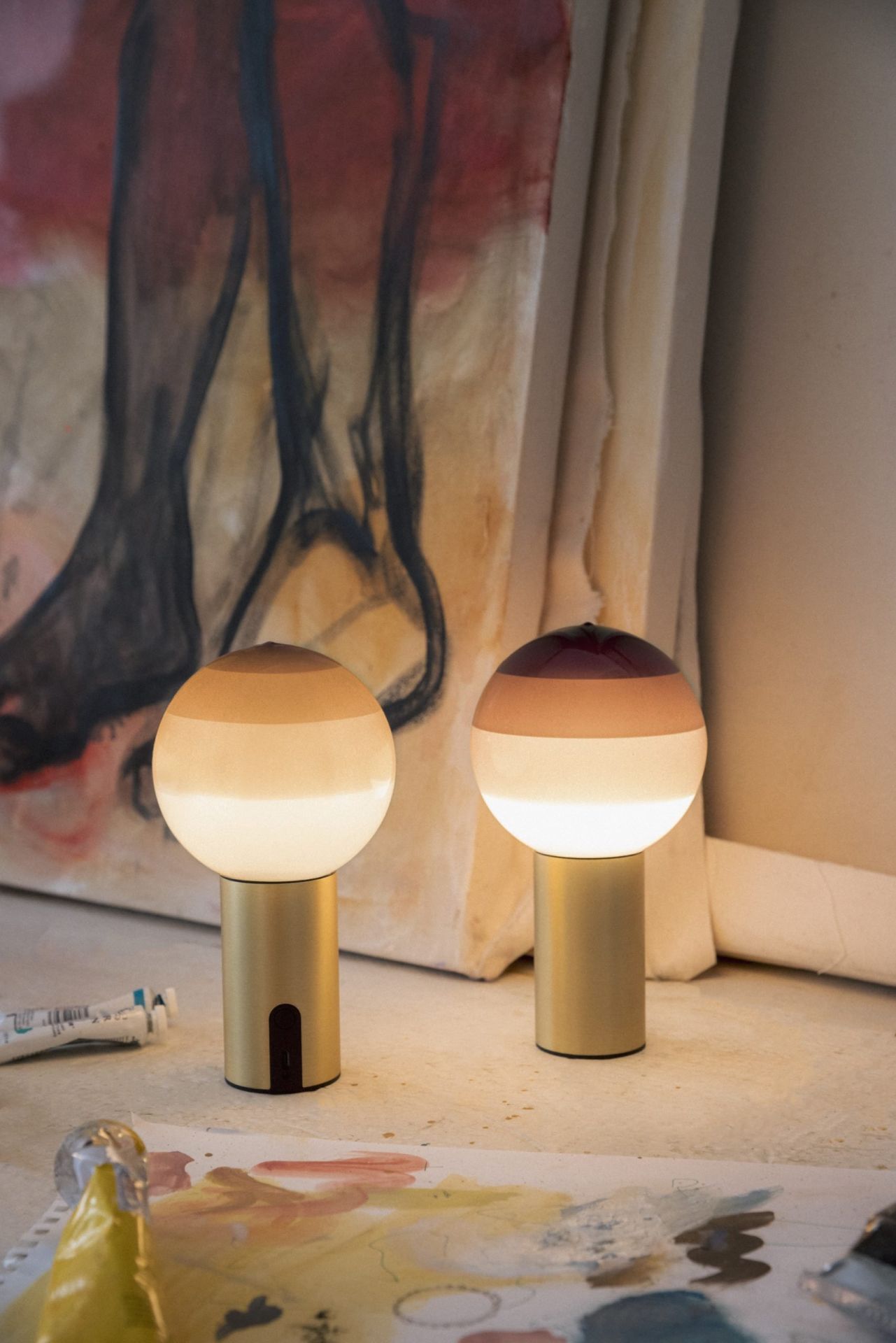 Zwei Marset Dipping Light S LED Tischleuchten mit goldenem Fuß und farbigem Glasschirm.