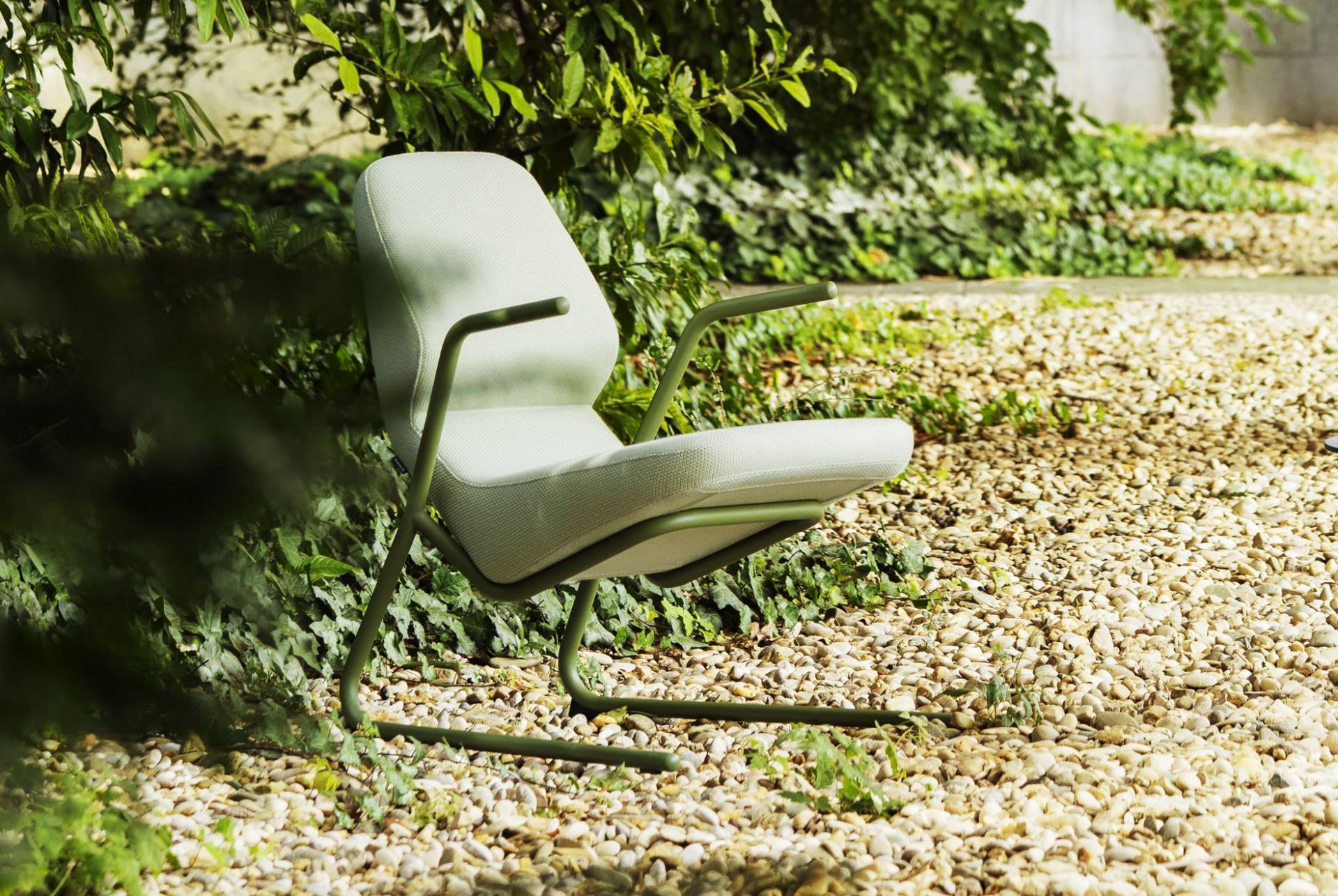 Heller Prostoria Oblique Sessel für drinnen und draußen, mit grünen Armlehnen und Gestell.