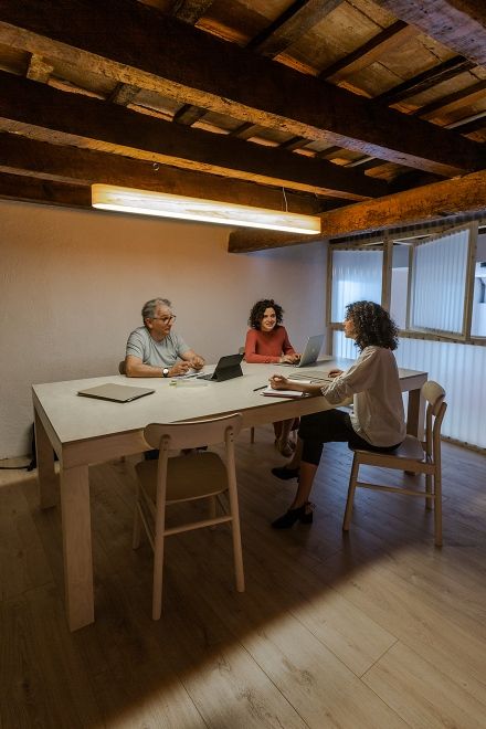 I-Club Pendelleuchte von LZF Lamps in Kirsche über einem Besprechungstisch mit Personen.