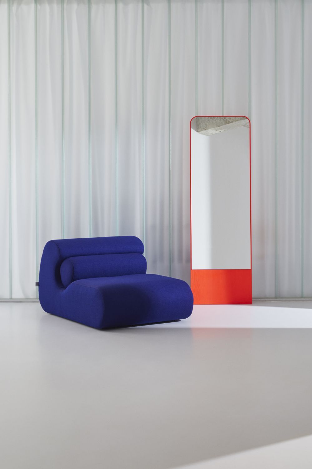 FRIEDRICH Spiegel Esche in Berliner Blau neben einem blauen Loungesessel vor Glaswand.