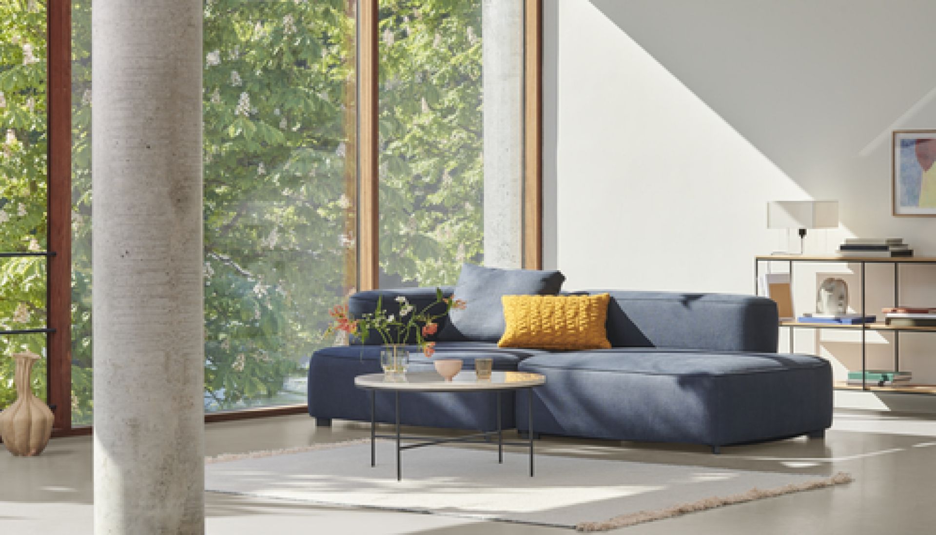 Wohnzimmer mit blauem Sofa, Tisch und Fritz Hansen Planner Regal zur Aufbewahrung von Büchern.