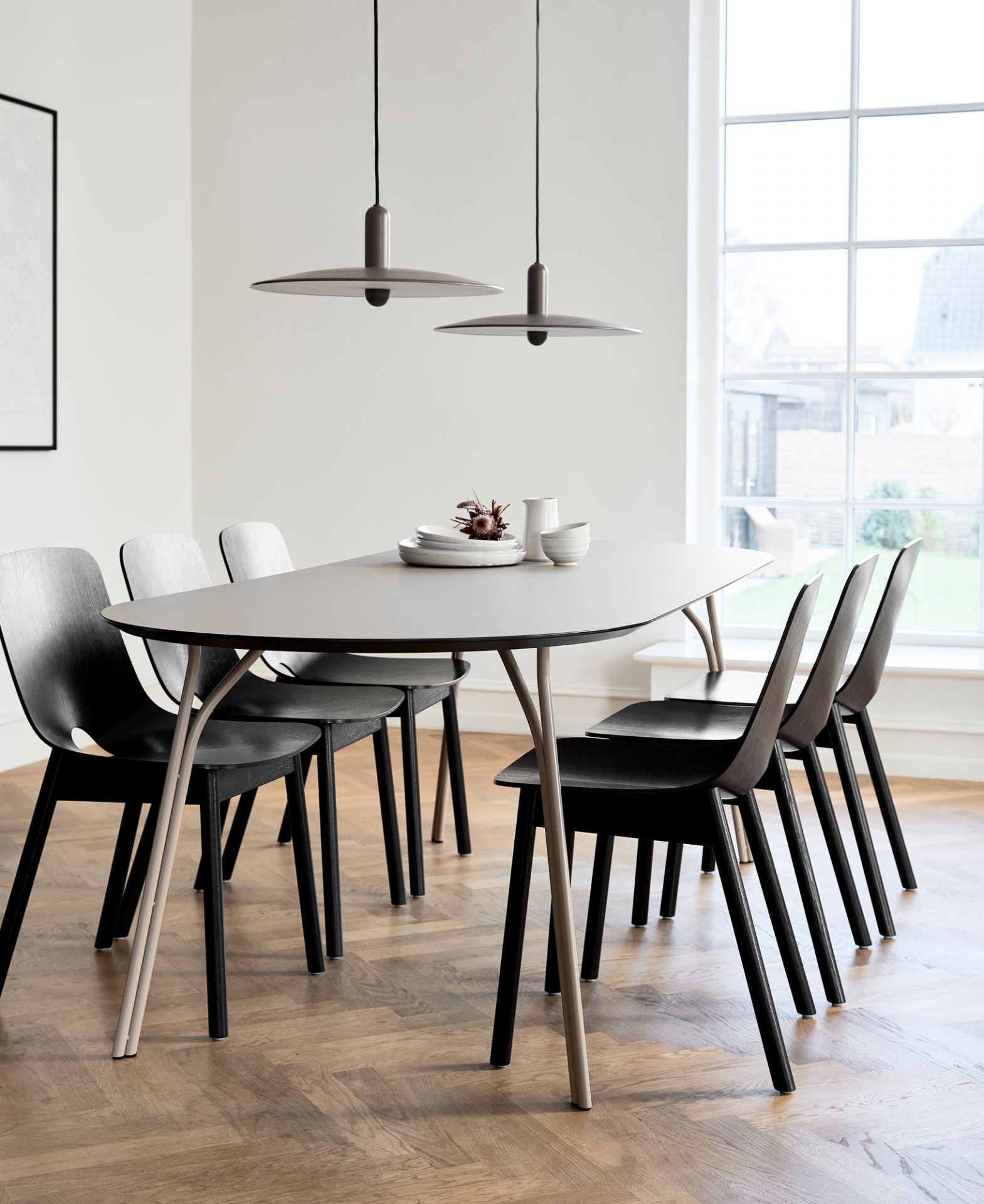 Eleganter Woud Tree Esstisch 90x220 mit sechs schwarzen Stühlen und stilvollen Pendelleuchten im hellen Esszimmer.