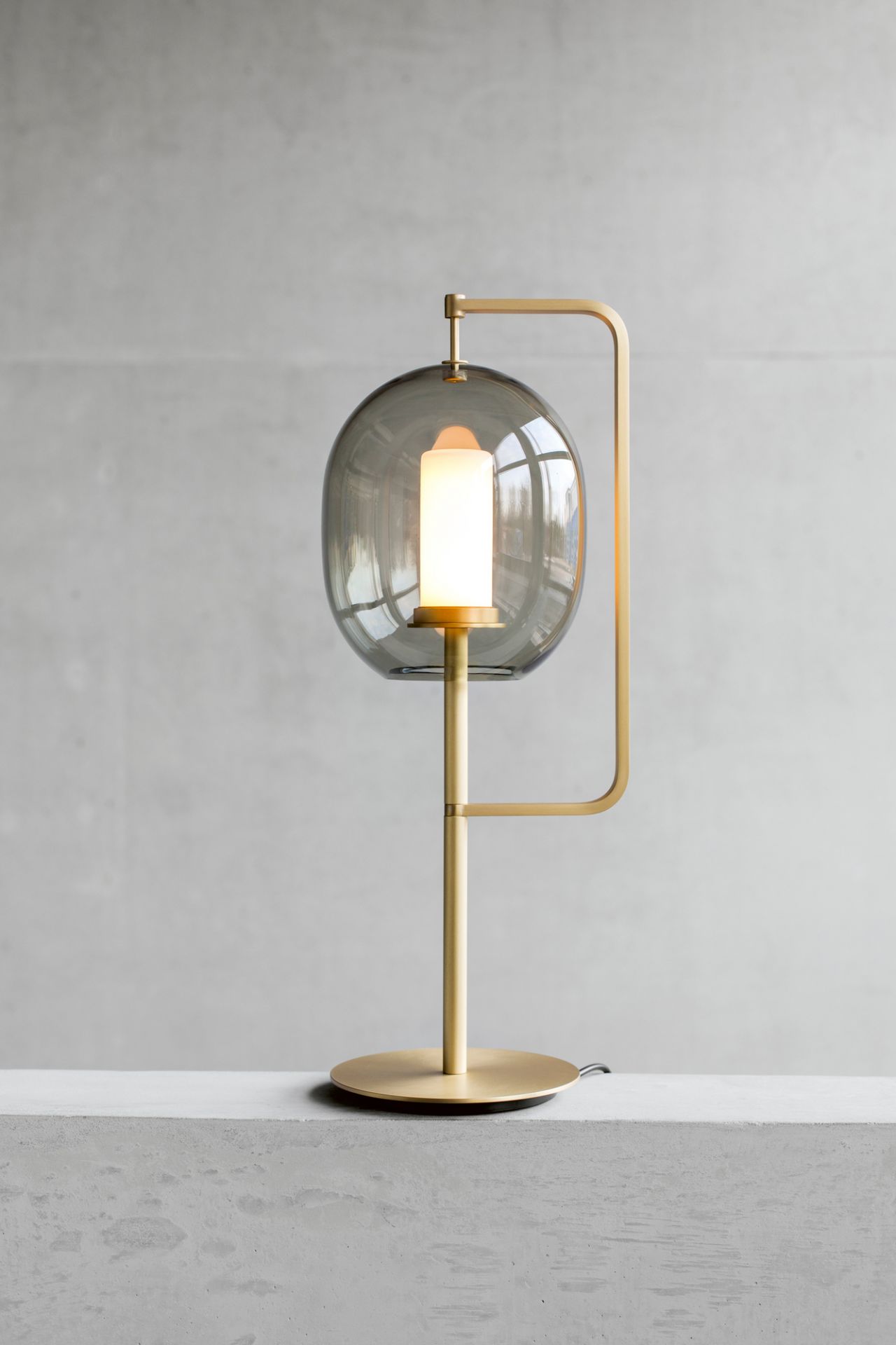 Lantern Light Tischleuchte Messing ClassiCon: Moderne Tischlampe mit grauem Glasschirm und Messinggestell.