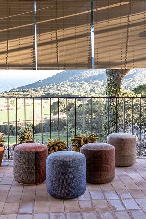 Mehrfarbige Shade Outdoor Pouf Hocker von Nanimarquina auf einer Terrasse mit Ausblick. Sitzhocker für den Garten.