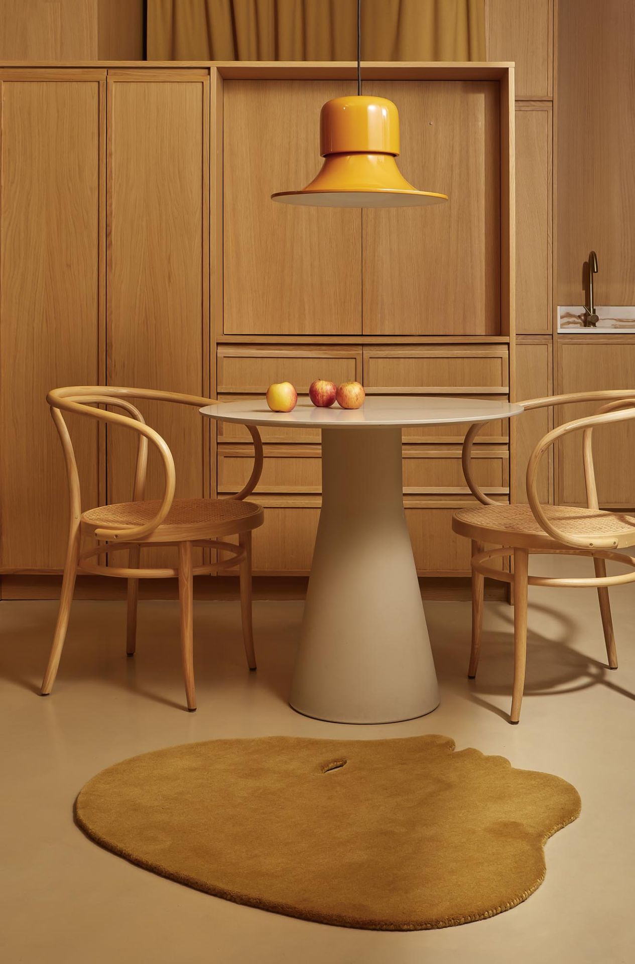 Nanimarquina Teppich Talk Talk in Blaugrün unter Esstisch mit Stühlen und gelber Lampe im modernen Interieur.