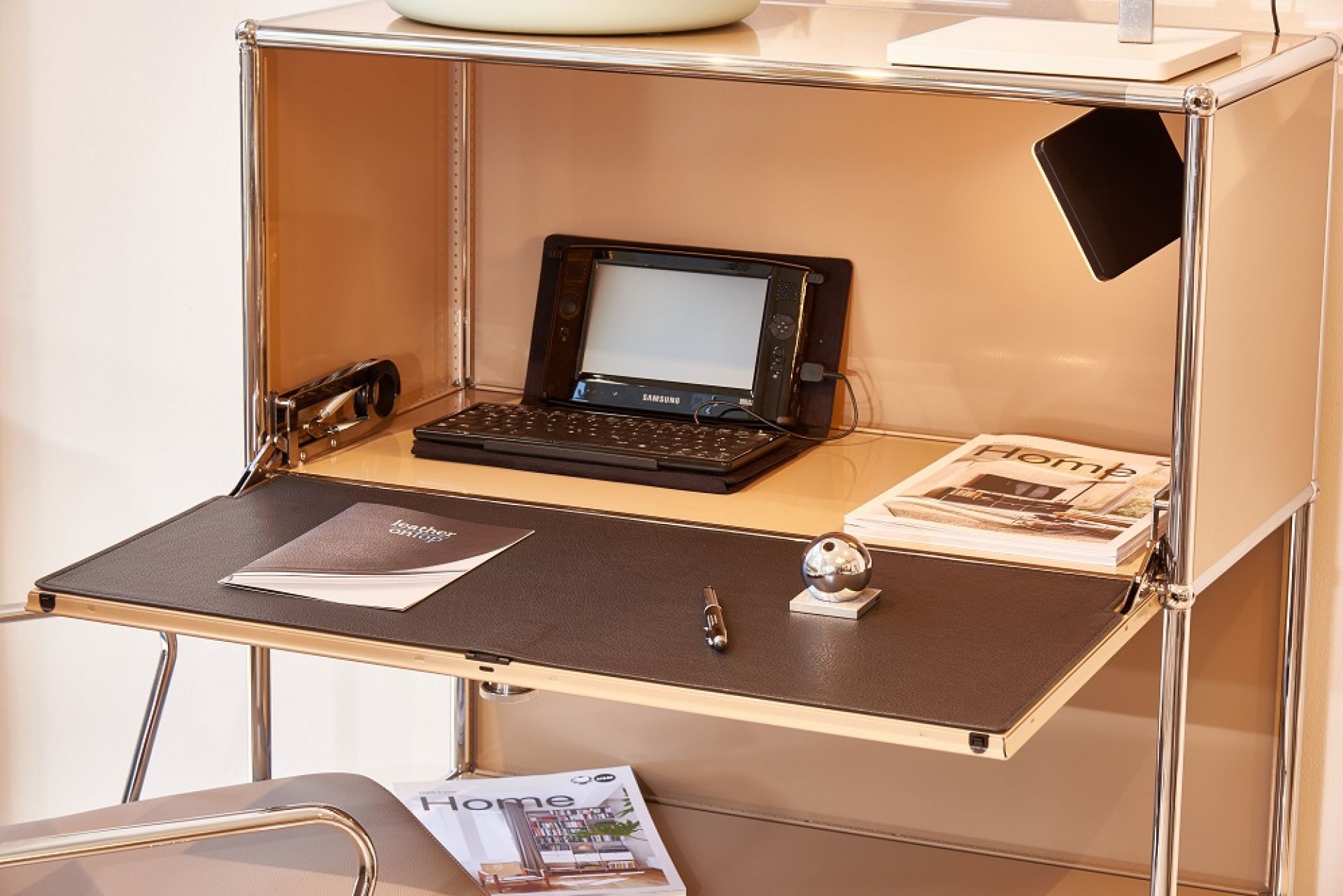 Nahaufnahme eines USM Schreibtisches mit brauner Lederauflage, Stift, Papier und Tablet.