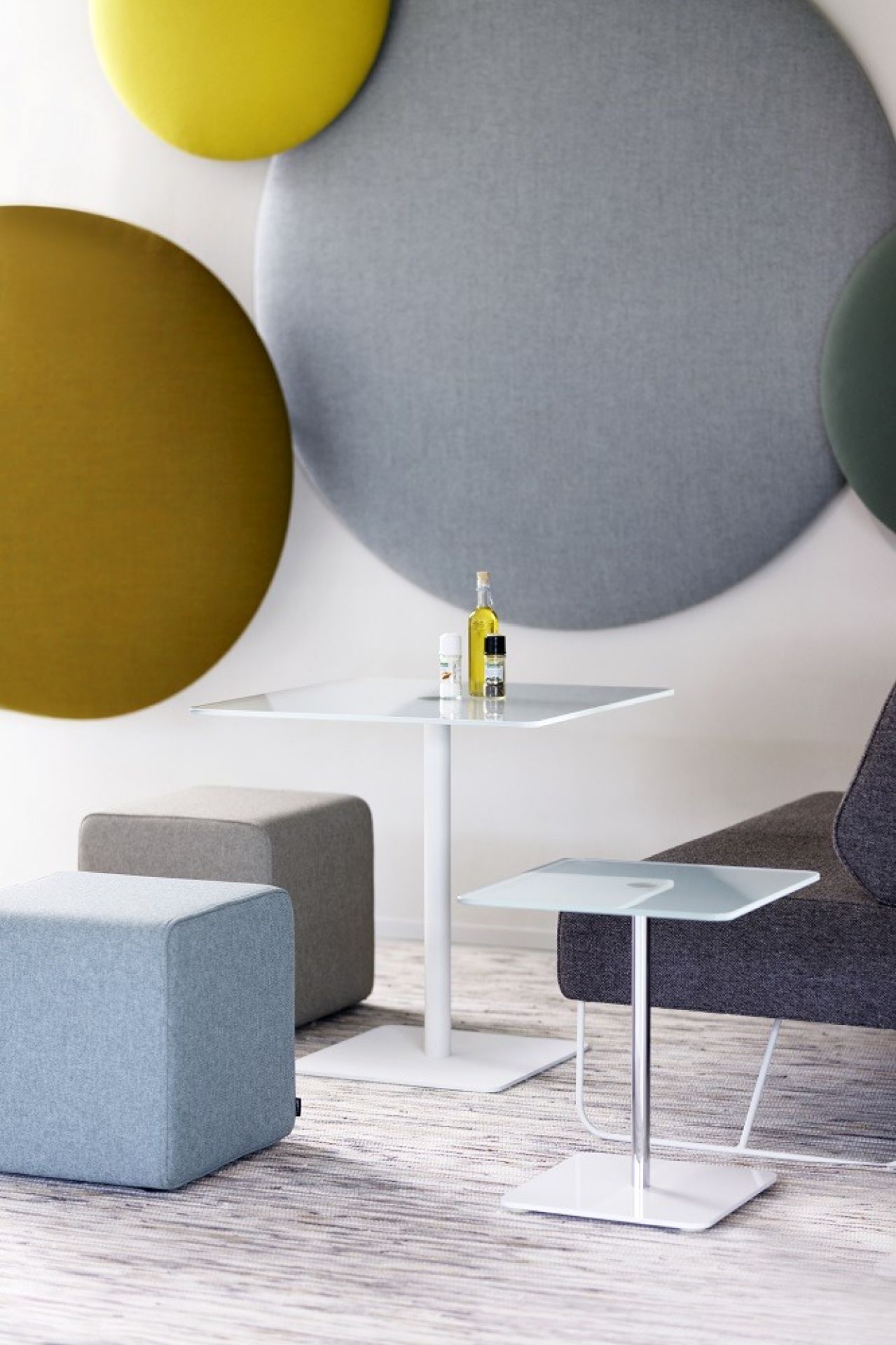 Pillow Round Wandpaneel als Akustikelement in Gelb, Grau, Grün und Ocker an einer Wand.