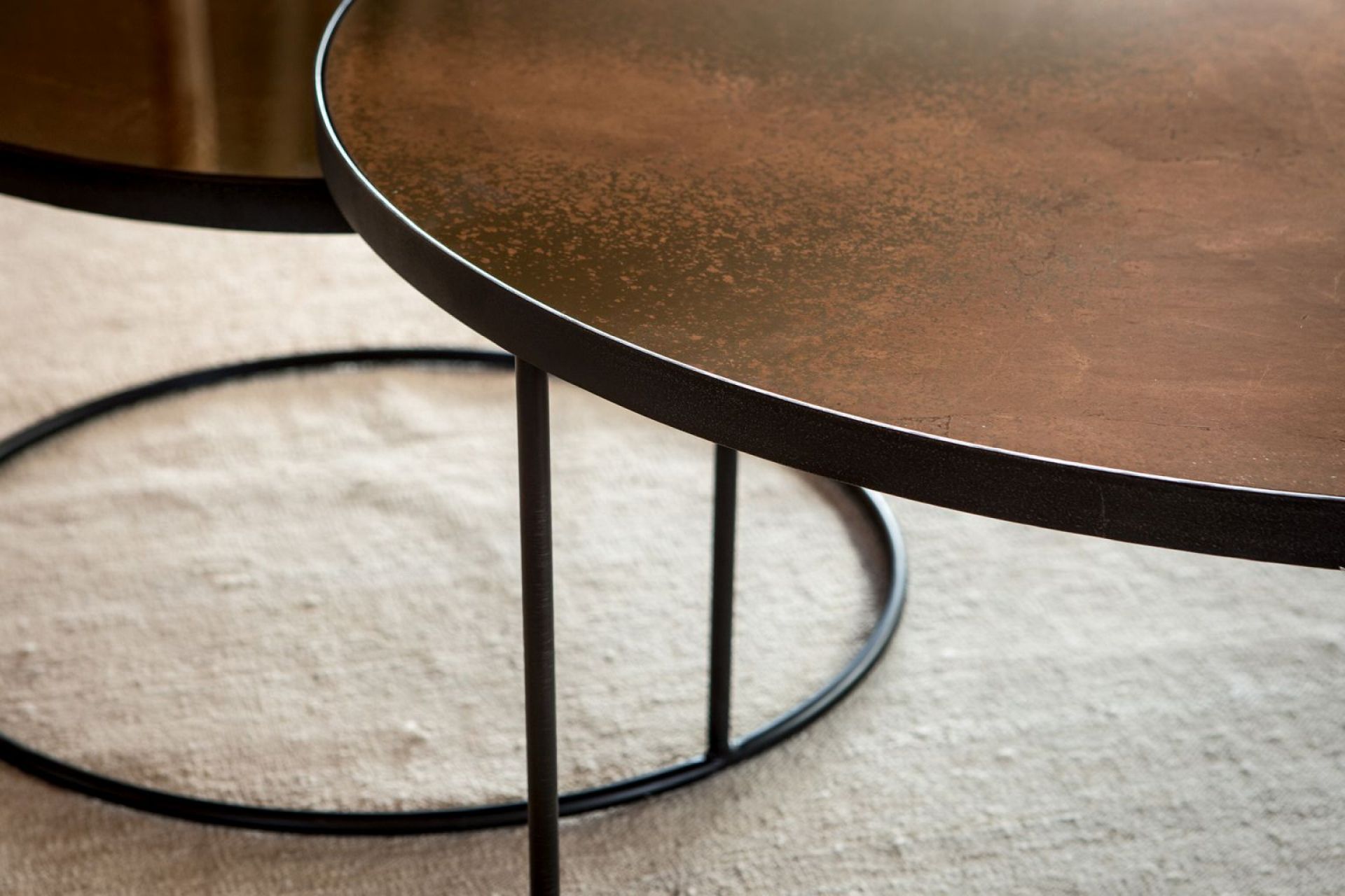 Detailaufnahme: Nesting Couchtisch 2er Set von Ethnicraft, bronze Tischplatten, schwarzes Metallgestell.