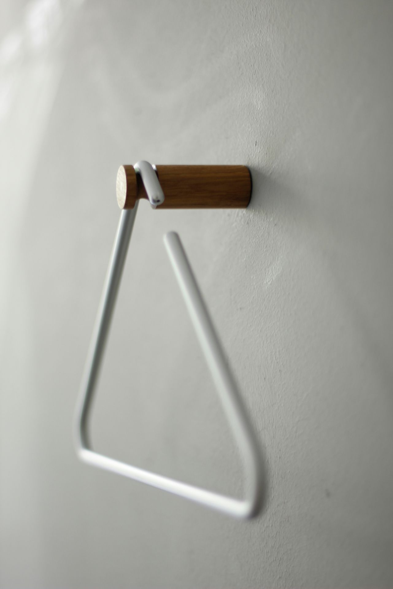 Roomsafari Triangle Kleiderbügel in Weiß an Wand montiert, minimalistisches Design für Garderobe und stilvolle Aufbewahrung.